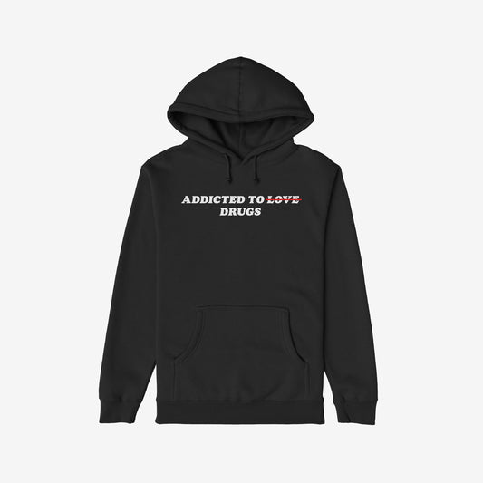 Black hoodie with Addicted To Love/Drugs in bold white and red text, featuring kangaroo pocket and drawstring hood. A thought-provoking piece reflecting personal struggles and self-awareness.