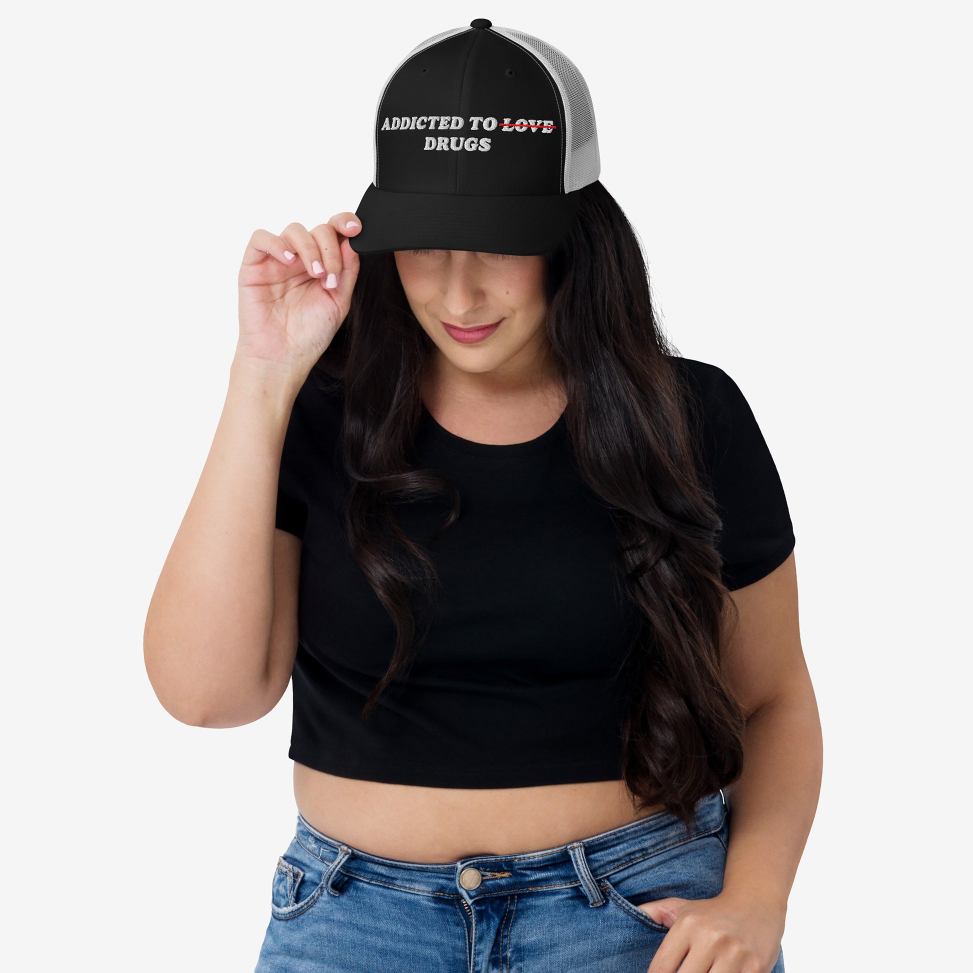 Woman wearing the Addicted To Love / Drugs Hat with "Love" crossed out and replaced by "Drugs" in embroidered text on black snapback.