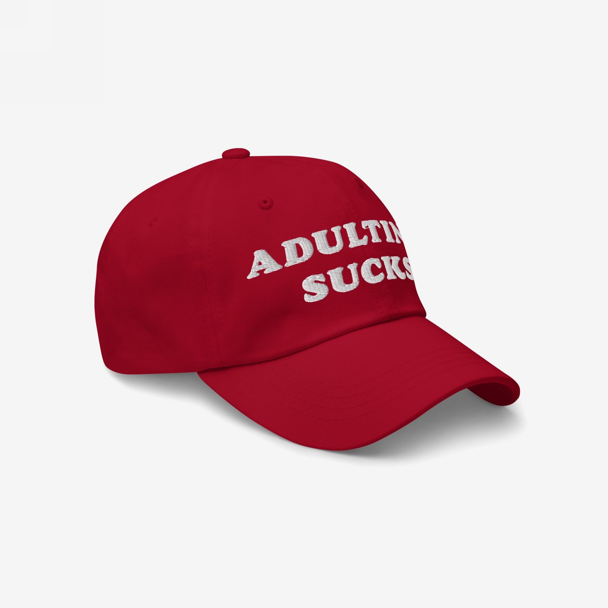 Red baseball-style cap with ADULTING SUCKS in white embroidery, embodying a relatable message for millennials and Gen Z. Ideal for casual wear, expressing frustration with adult responsibilities.