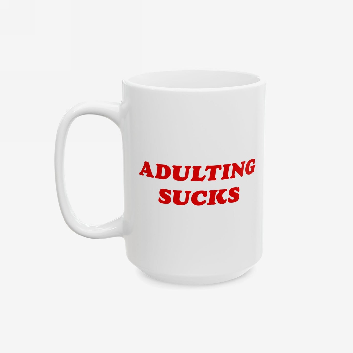 Adulting Sucks Mug with bold red lettering on white ceramic, expressing relatable frustration. Perfect for millennials facing daily challenges, this durable, dishwasher-safe mug supports Amnesty International. Available in 11 oz. and 15 oz.