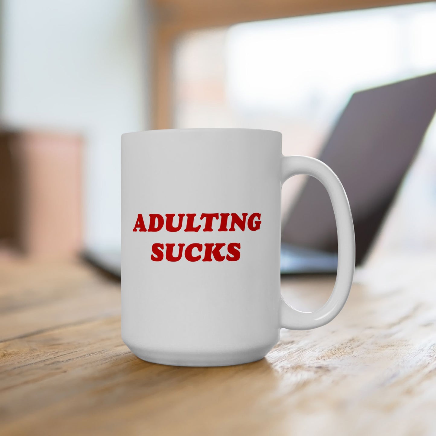 A white ceramic mug with ADULTING SUCKS in bold red letters, perfect for expressing morning frustrations. Ideal for anyone navigating modern adulthood, this mug offers humor and resilience in every sip.