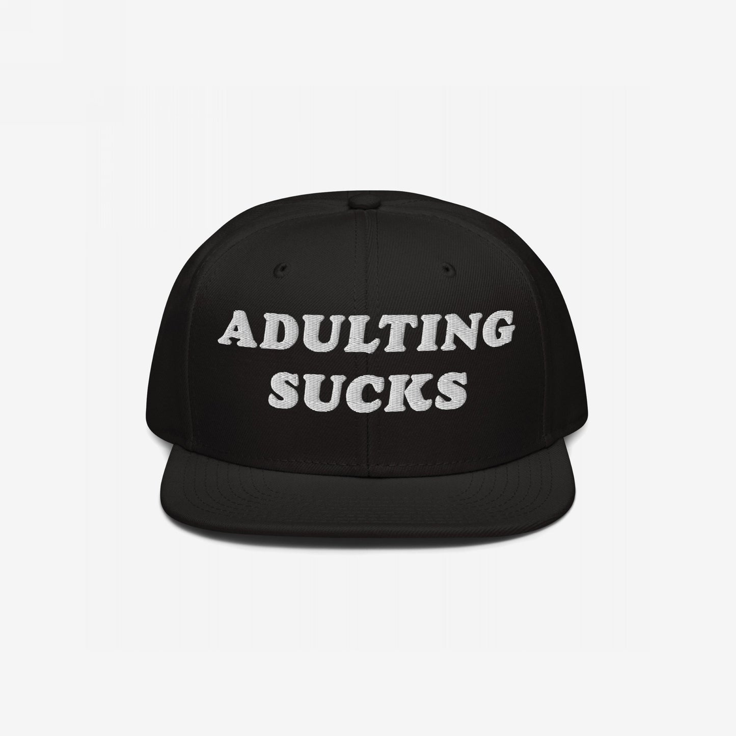 Black flat-brim snapback hat with ADULTING SUCKS embroidered in bold white letters, reflecting a candid, humorous take on life's challenges. Perfect for expressing shared frustrations while supporting a meaningful cause.