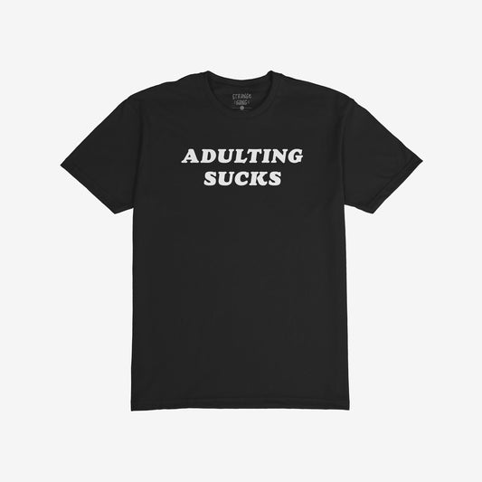 Adulting Sucks T-shirt featuring bold white block letters on a plain black background, capturing a playful, retro vibe. Perfect for expressing the frustrations of grown-up life with a touch of humor.