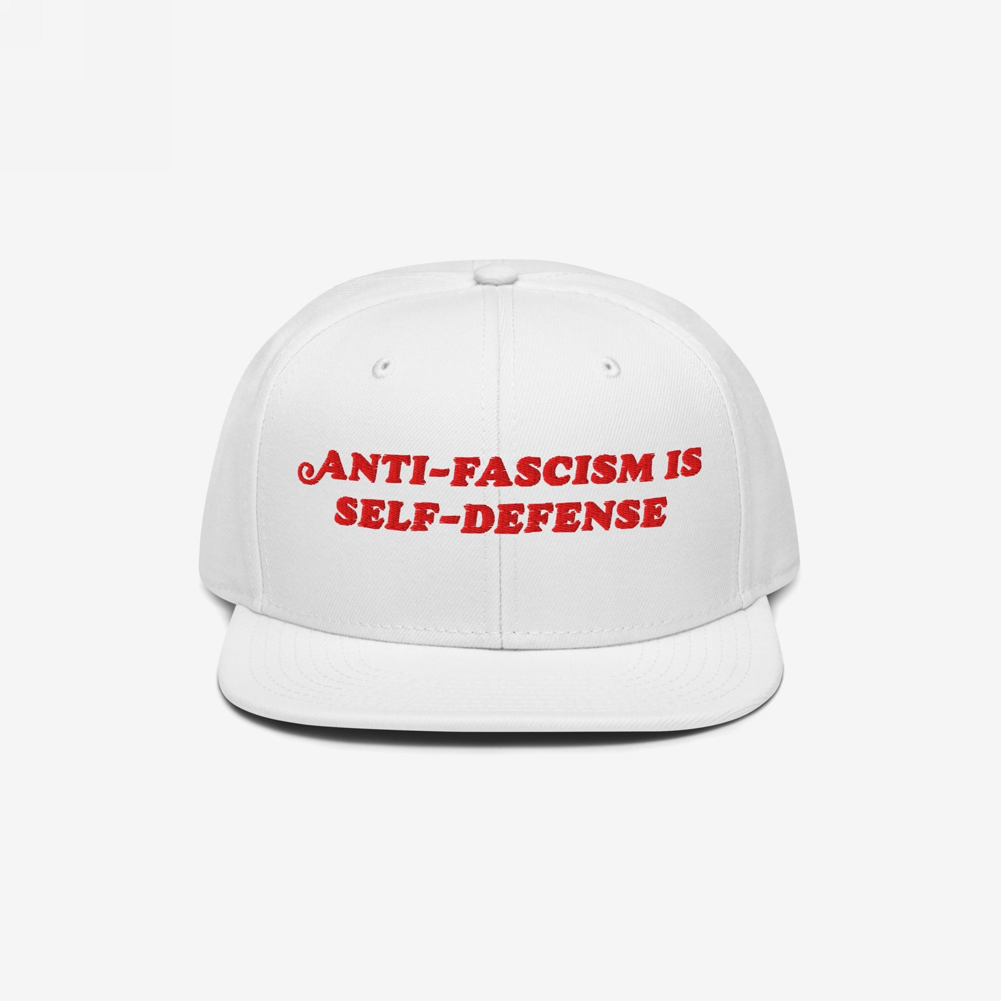 White flat-brimmed cap featuring bold red embroidery reading ANTI-FASCISM IS SELF-DEFENSE for activists and allies, embodying a vintage, unapologetic stance against fascism.