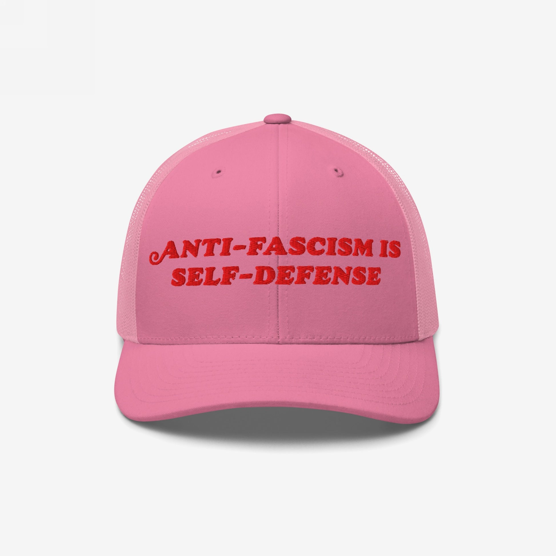 Pink trucker-style baseball cap with red embroidered “ANTI-FASCISM IS SELF-DEFENSE” text, embodying activist spirit. Ideal for allies and organizers committed to human rights and resisting fascism through fashion.
