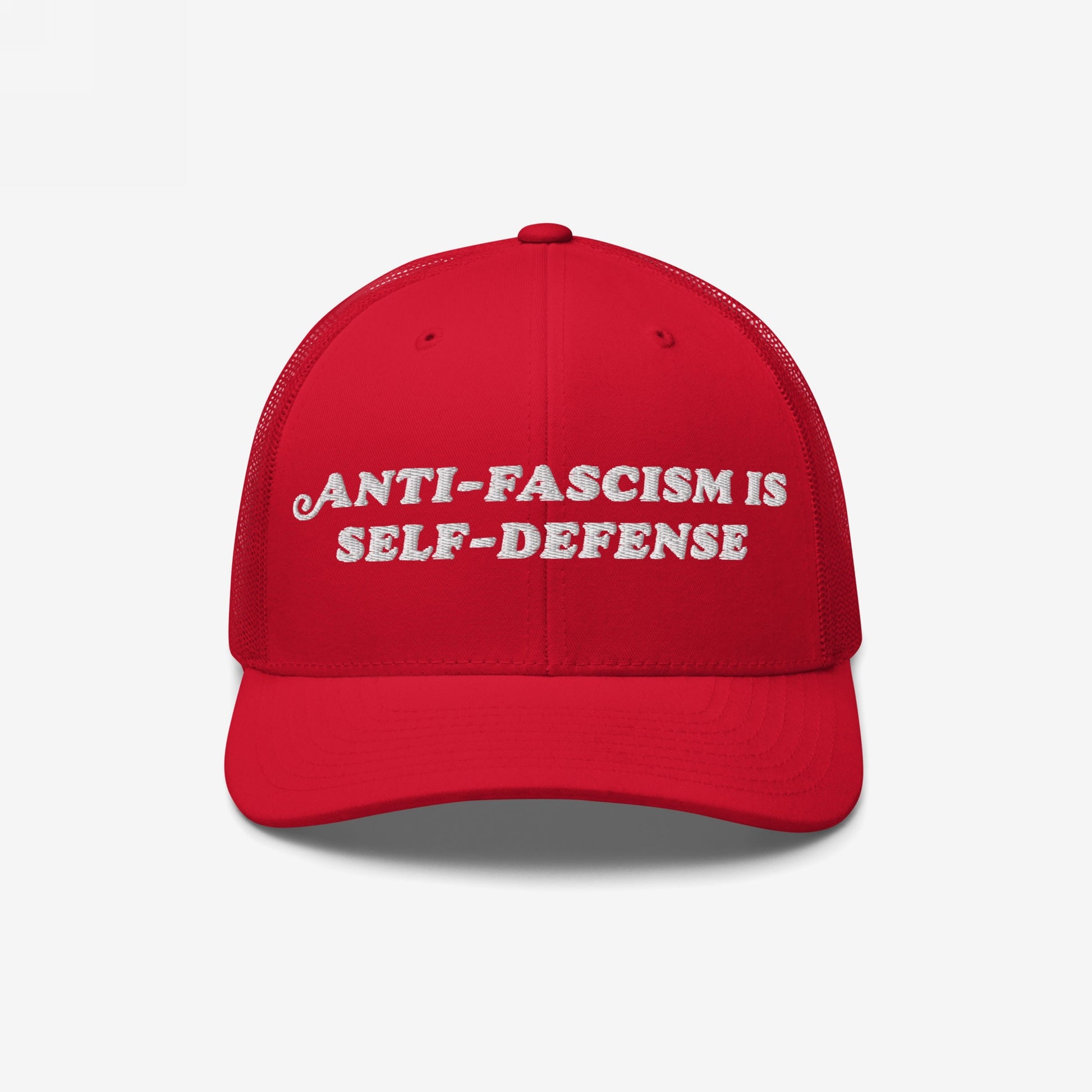The image features the Anti Fascism Is Self Defense Hat, a red mesh-back trucker cap with ANTI-FASCISM IS SELF-DEFENSE embroidered in white, embodying activist spirit and supporting ACLU.