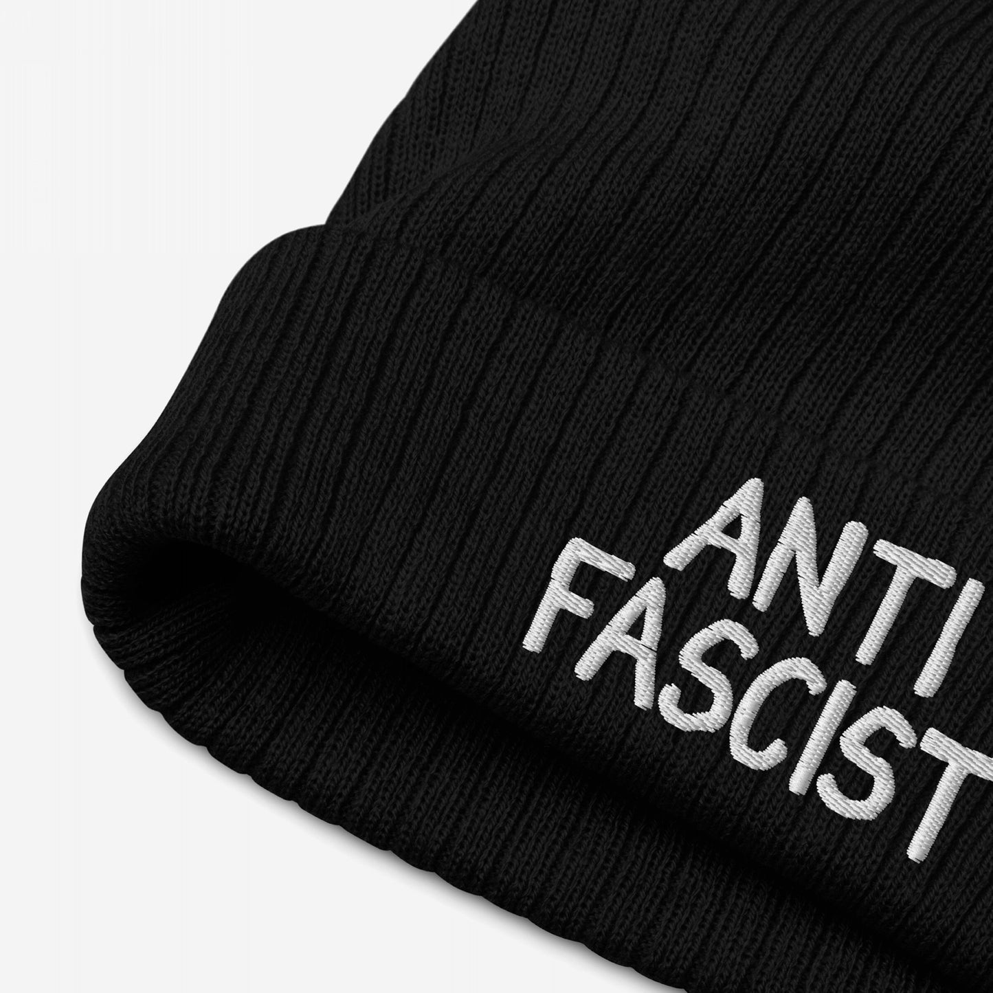 Black rib-knit beanie hat with ANTI FASCIST embroidered in white on the cuff. Ethically made, gender-free. Anti-Fascist Hat embodies protest fashion with a soft fit and hand-drawn embroidery.