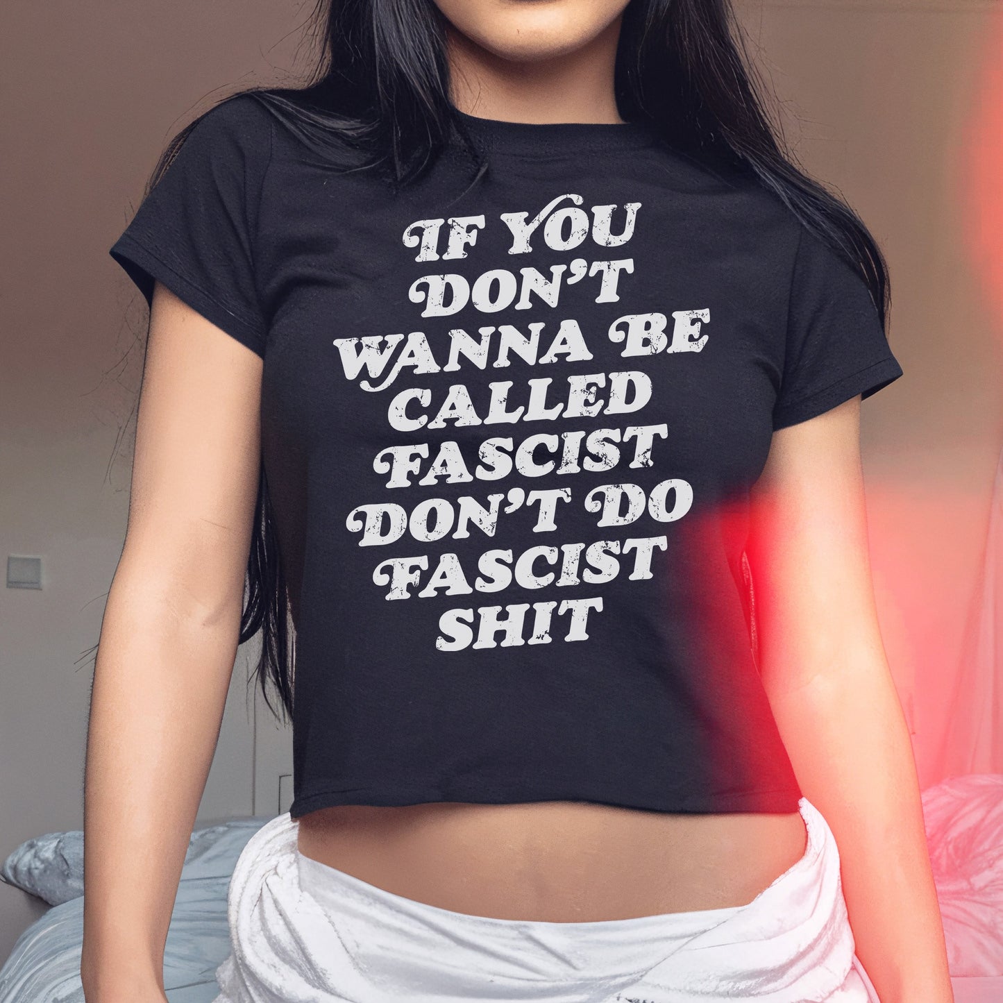 Anti-Fascist Retro Women's Baby Tee with bold slogan, If you don’t wanna be called fascist don’t do fascist shit, worn by a young woman, embodies a powerful statement for equality and activism.