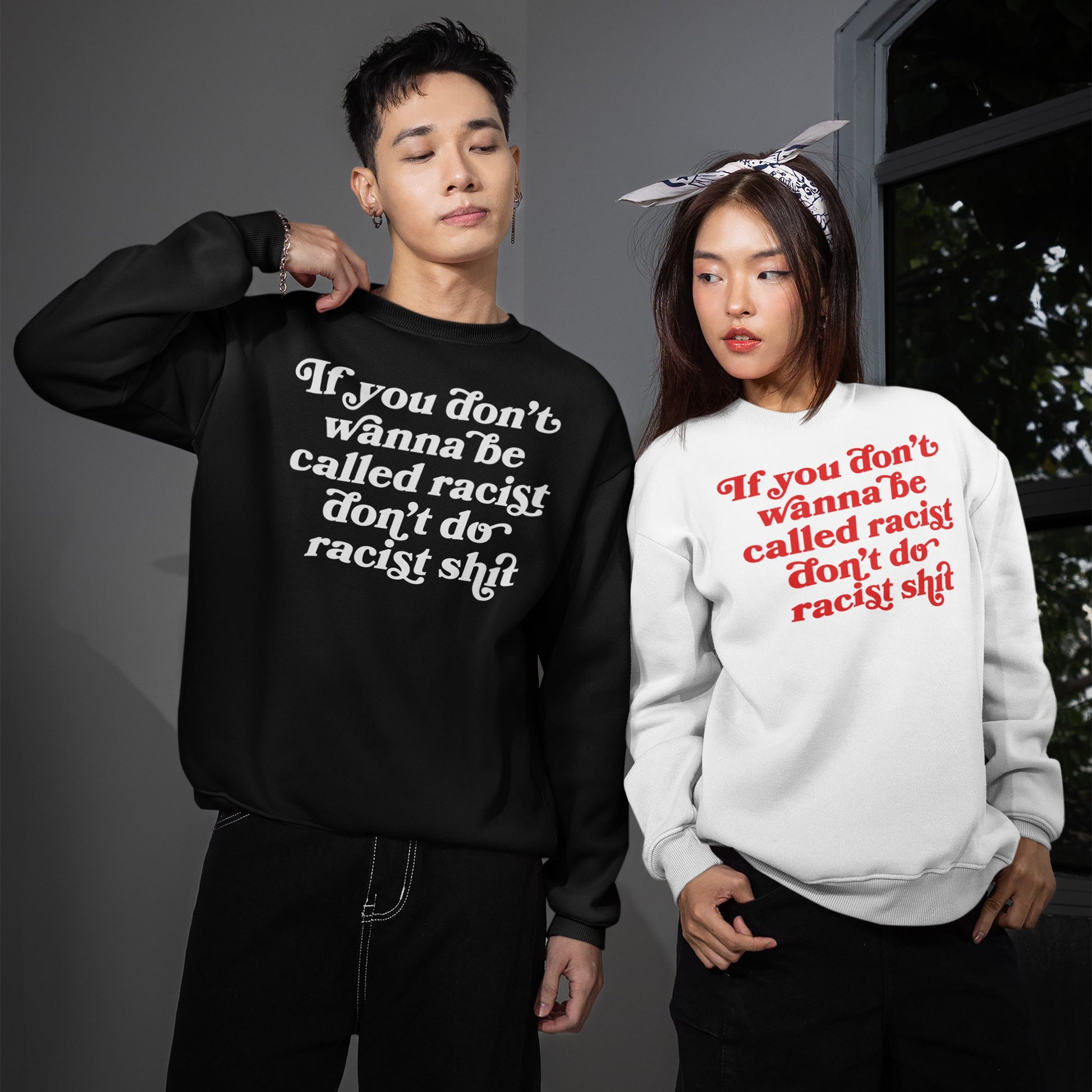 Anti-Racist Hoodie & Sweatshirt EU: Two models showcase black and white versions, both with bold anti-racist slogans. The man adjusts his collar; the woman sports a bandana, embodying defiant style.