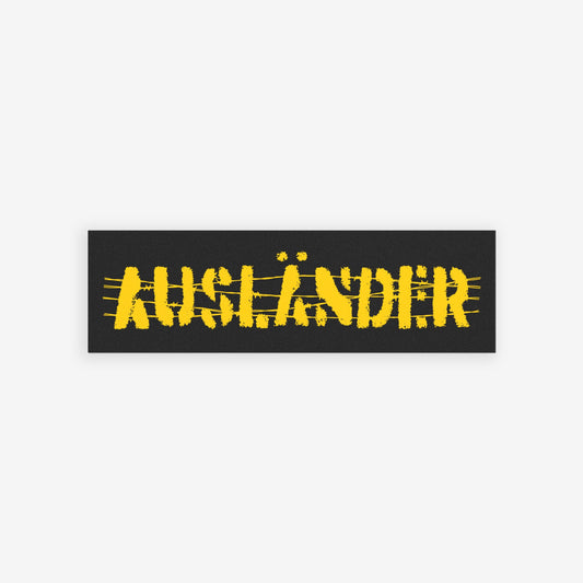 Ausländer Sticker & Magnet featuring a distressed, stencil-style AUFZÄNDER design on a black banner. The background shows a blurred crowd, symbolizing solidarity and strength against nationalism and oppression.