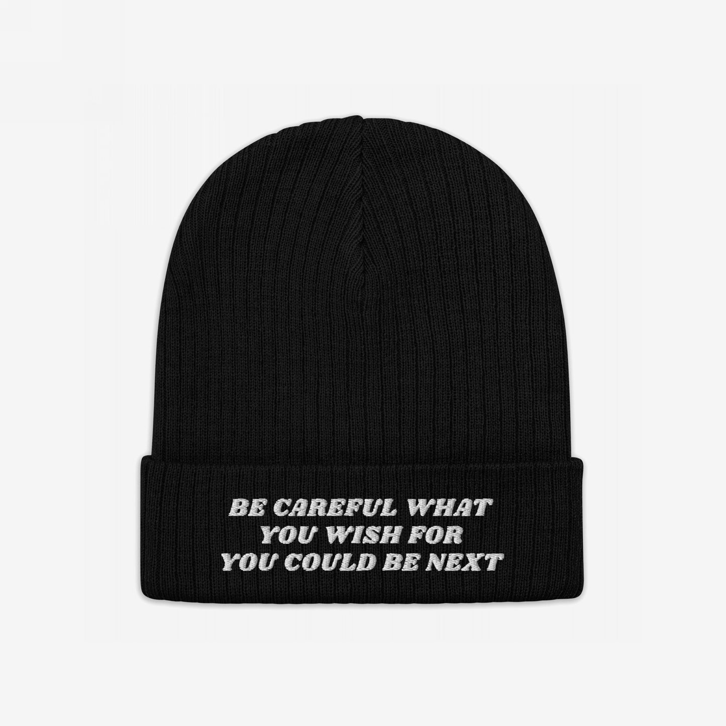 Black rib-knit Be Careful Hat with a folded cuff, featuring white embroidered text warning Be Careful What You Wish For, You Could Be Next, conveying a bold, activist message.
