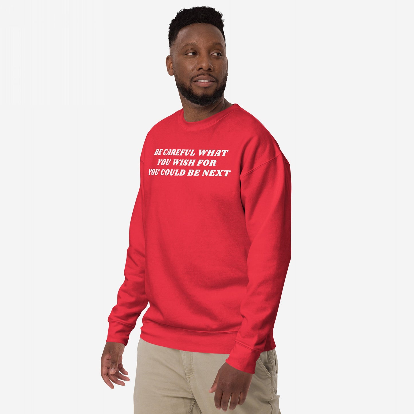Man wears the Be Careful Hoodie & Sweatshirt, featuring a bold message challenging authoritarianism. The bright red crewneck displays thought-provoking white text, embodying modern rebellion with a Y2K-inspired design.