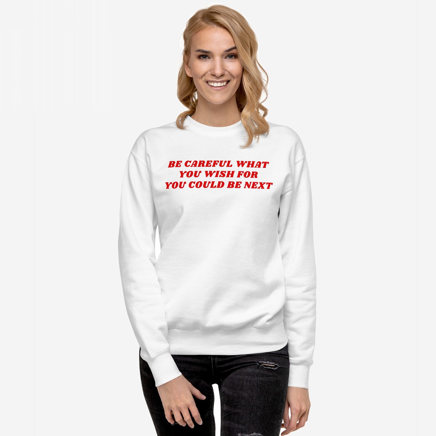 A smiling woman models the Be Careful Hoodie & Sweatshirt, featuring a bold red warning slogan on a white crew-neck, embodying modern rebellion against authoritarianism.