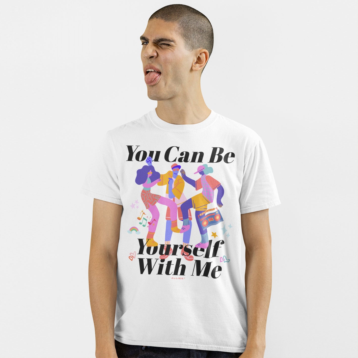 Model wearing Be Yourself T-shirt with vibrant dancing figures, musical notes, and empowering text. The playful expression captures the shirt's message of authenticity and inclusivity.