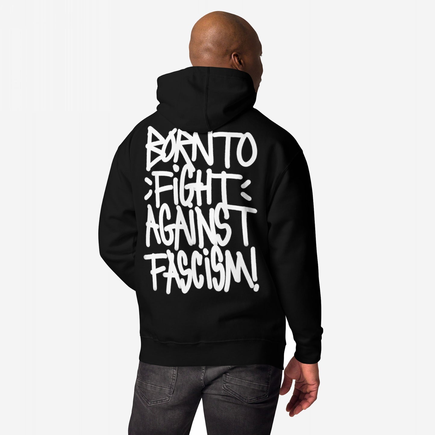 Person wearing the Born To Fight Against Fascism Graffiti Hoodie, showcasing bold white graffiti text on the back. The design embodies defiance and rebellion, paired with dark jeans, emphasizing a message of resistance.