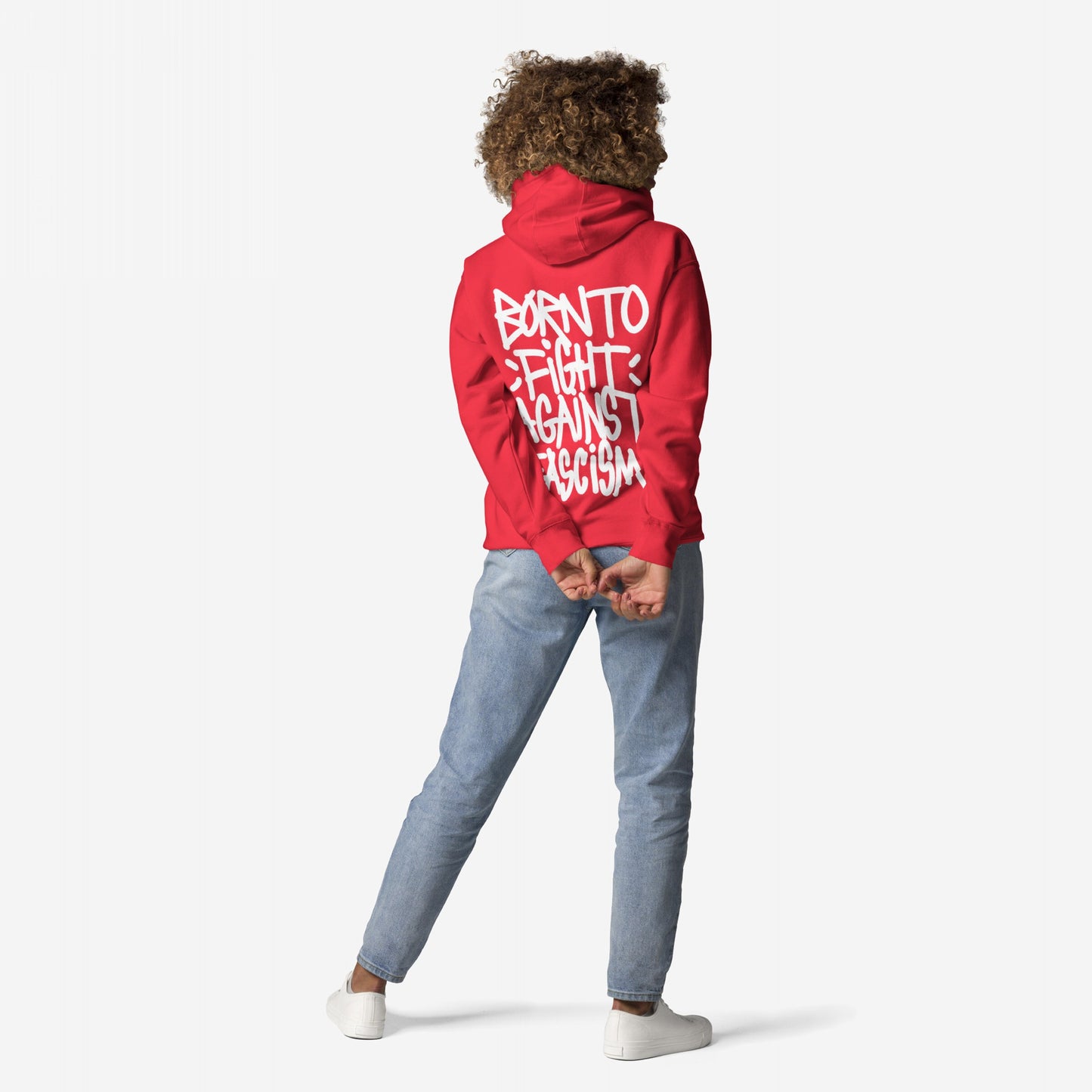 Person in the Born To Fight Against Fascism Graffiti Hoodie, showcasing bold white lettering, paired with light-wash jeans and white sneakers, embodying rebellion and resistance.