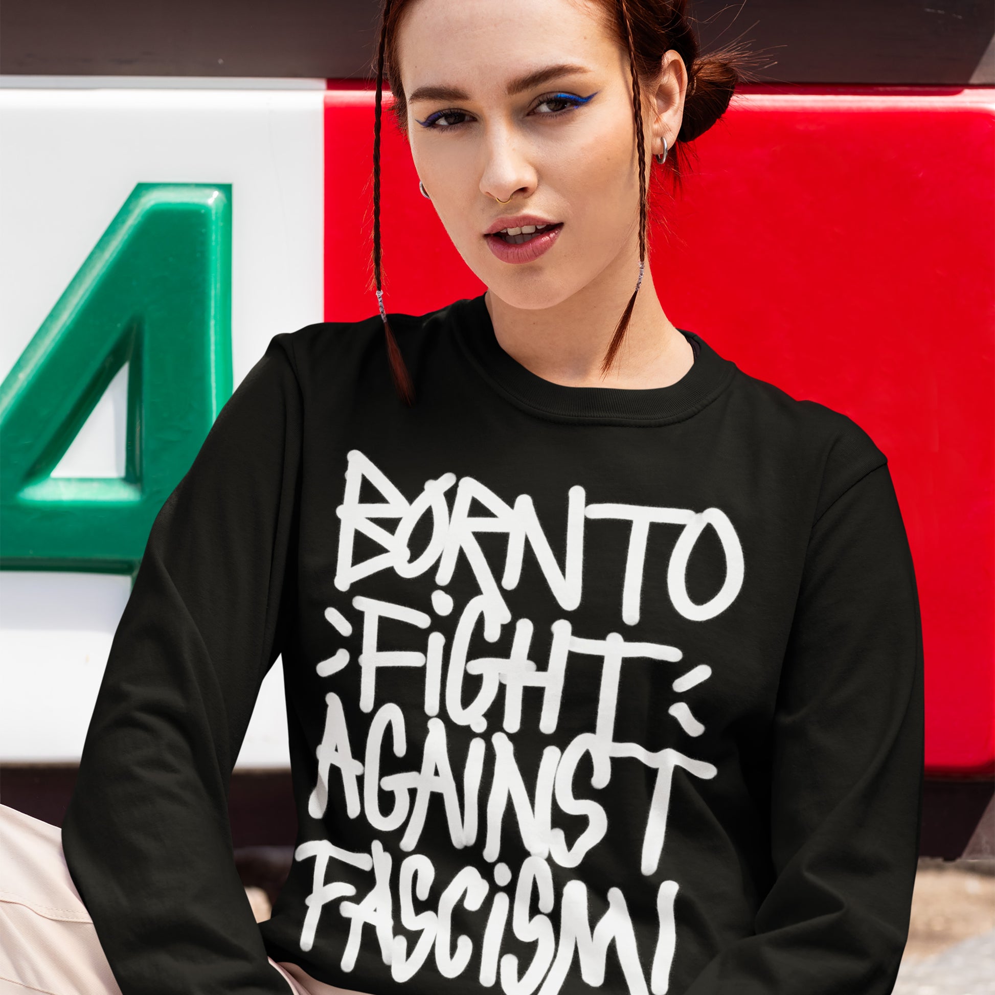 Born To Fight Against Fascism Graffiti Shirt worn by a young woman with braids, exuding street-style activism. The shirt's bold lettering embodies resistance and rebellion, supporting ACLU's fight against tyranny.