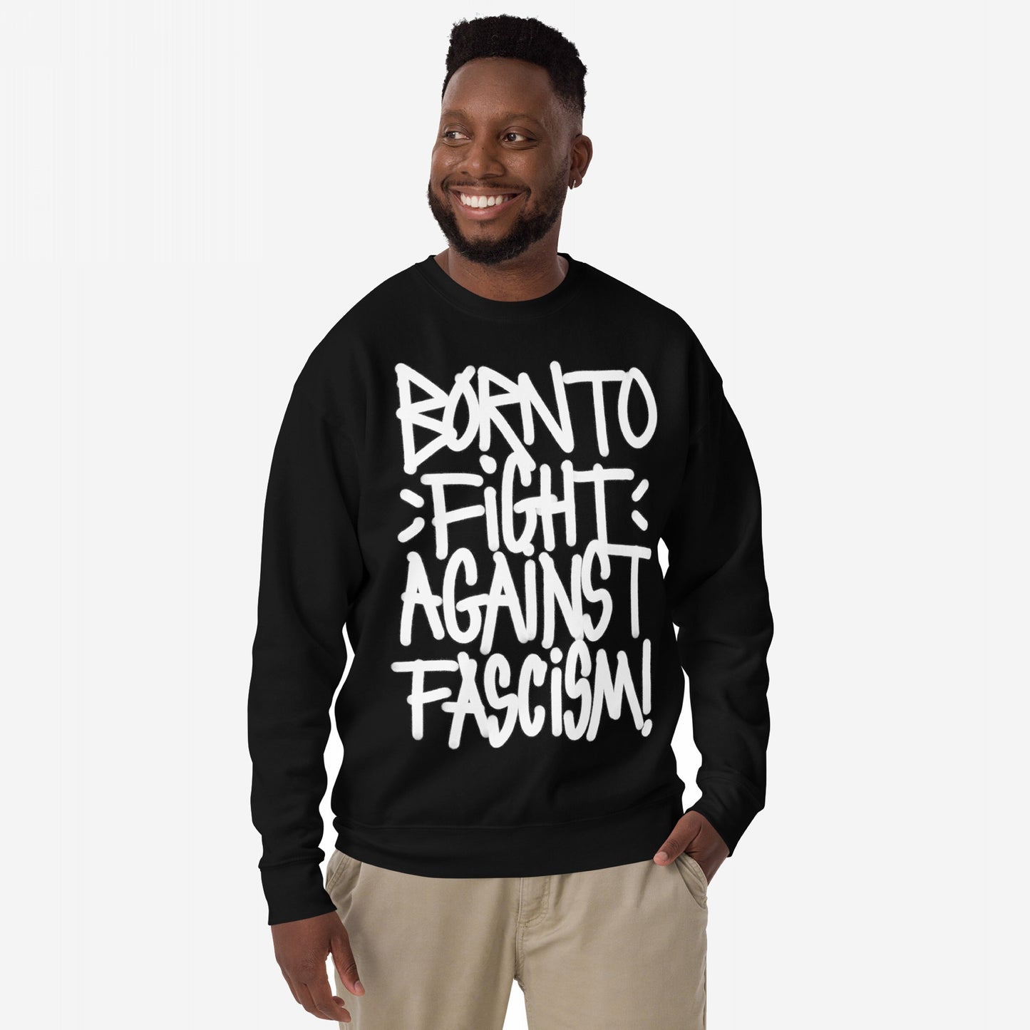 Smiling Black man wearing the Born To Fight Against Fascism Graffiti Hoodie & Sweatshirt with bold white graffiti-style text, light-khaki pants, embodying defiance and rebellion.
