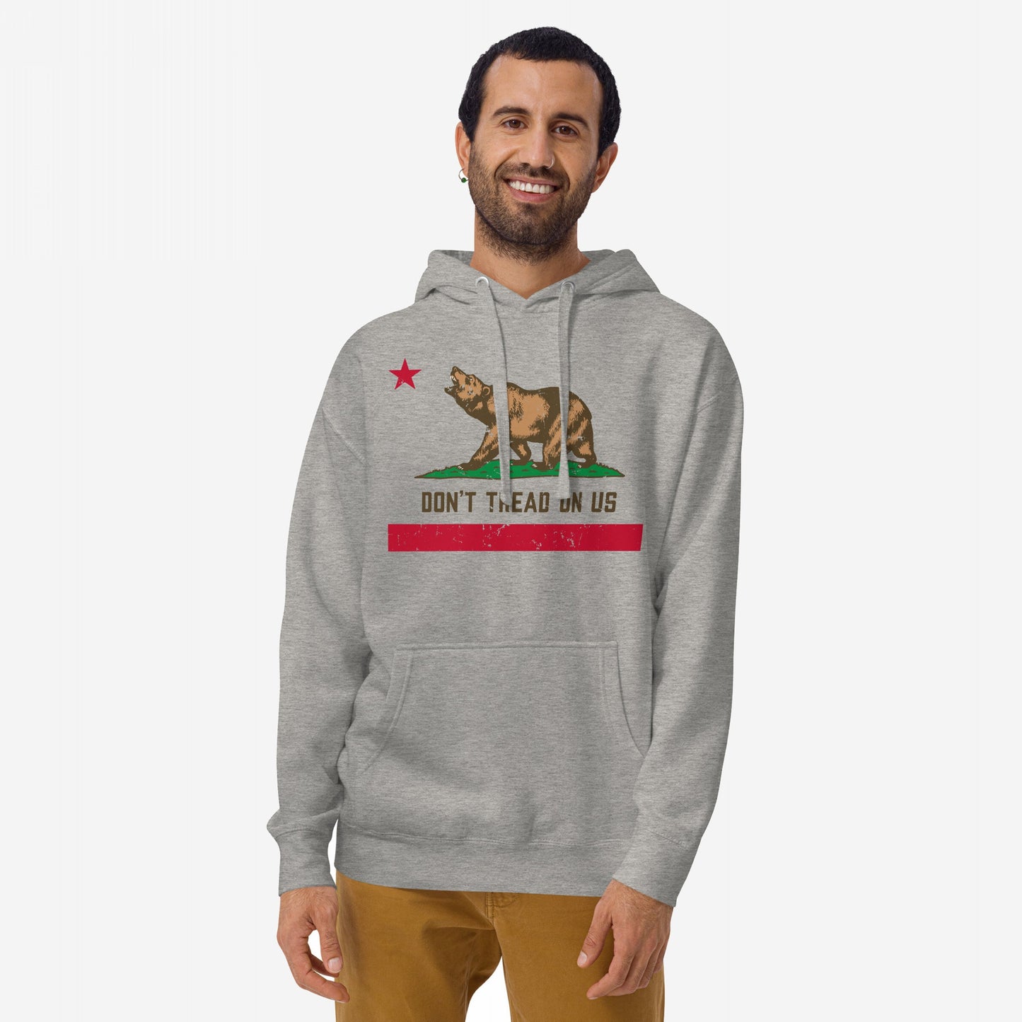 California Gadsden Flag Hoodie & Sweatshirt featuring a stylized brown bear, red star, and “DON’T TREAD ON US” slogan, modeled by a smiling man in tan pants against a white background.