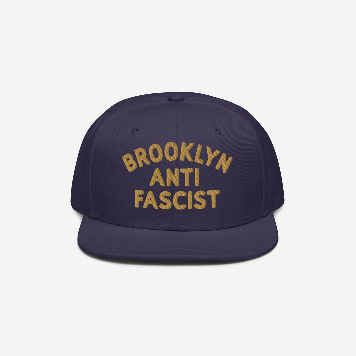 Custom Anti-Fascist Snapback Hat featuring BROOKLYN / ANTI / FASCIST embroidered in mustard-gold on a dark-navy cap. This adjustable, structured hat merges style with a bold message against fascism.