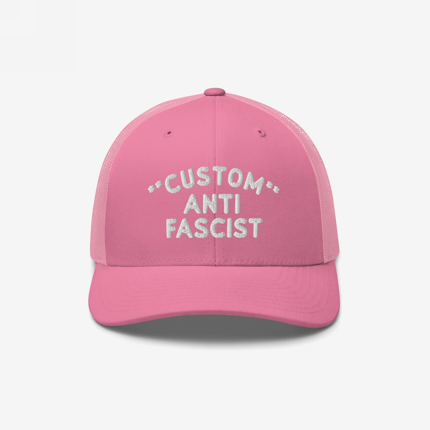 Custom Anti-Fascist Trucker Hat features a pink design with white CUSTOM ANTI FASCIST embroidery. The hat includes mesh panels and an adjustable snapback, conveying a bold anti-fascist message.