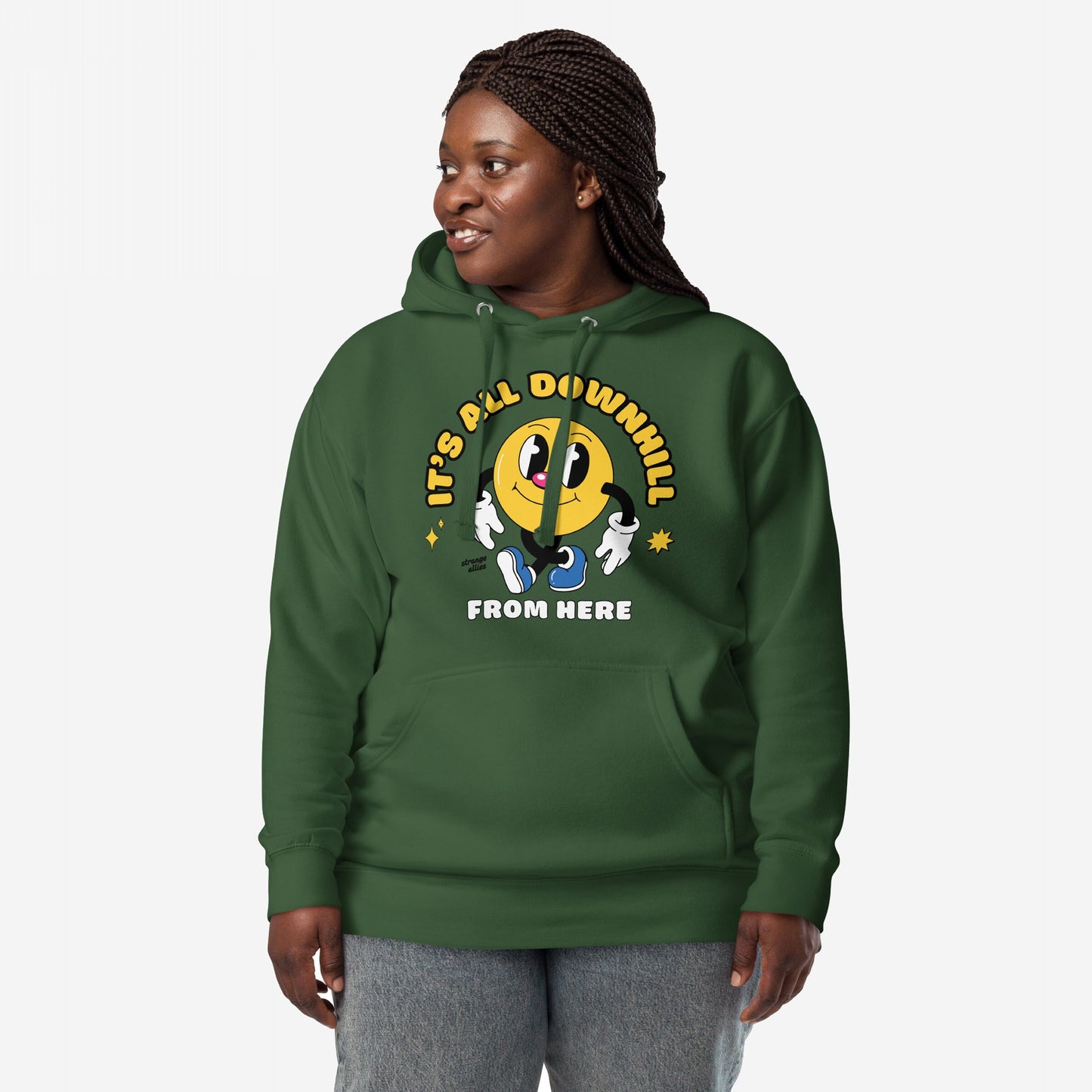 Dark-skinned woman models the Downhill Hoodie & Sweatshirt, featuring a cartoon yellow smiley and the slogan It’s all downhill from here, embodying a humorous, realist perspective in cozy fleece.
