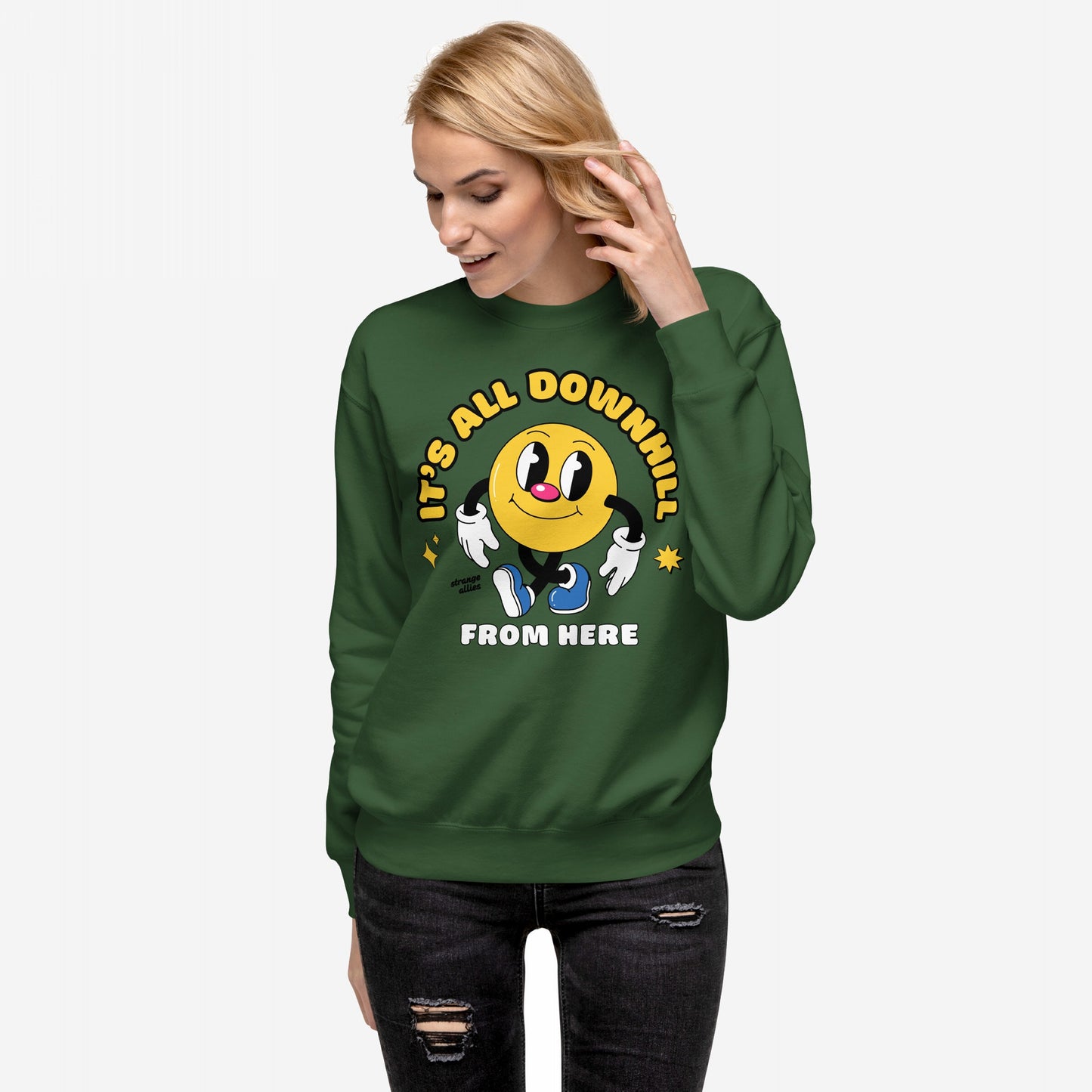 Model wearing the Downhill Hoodie & Sweatshirt with a cartoon-style yellow smiley, gloved hands, and blue sneakers, paired with distressed black jeans, embodying a laid-back, realist vibe.