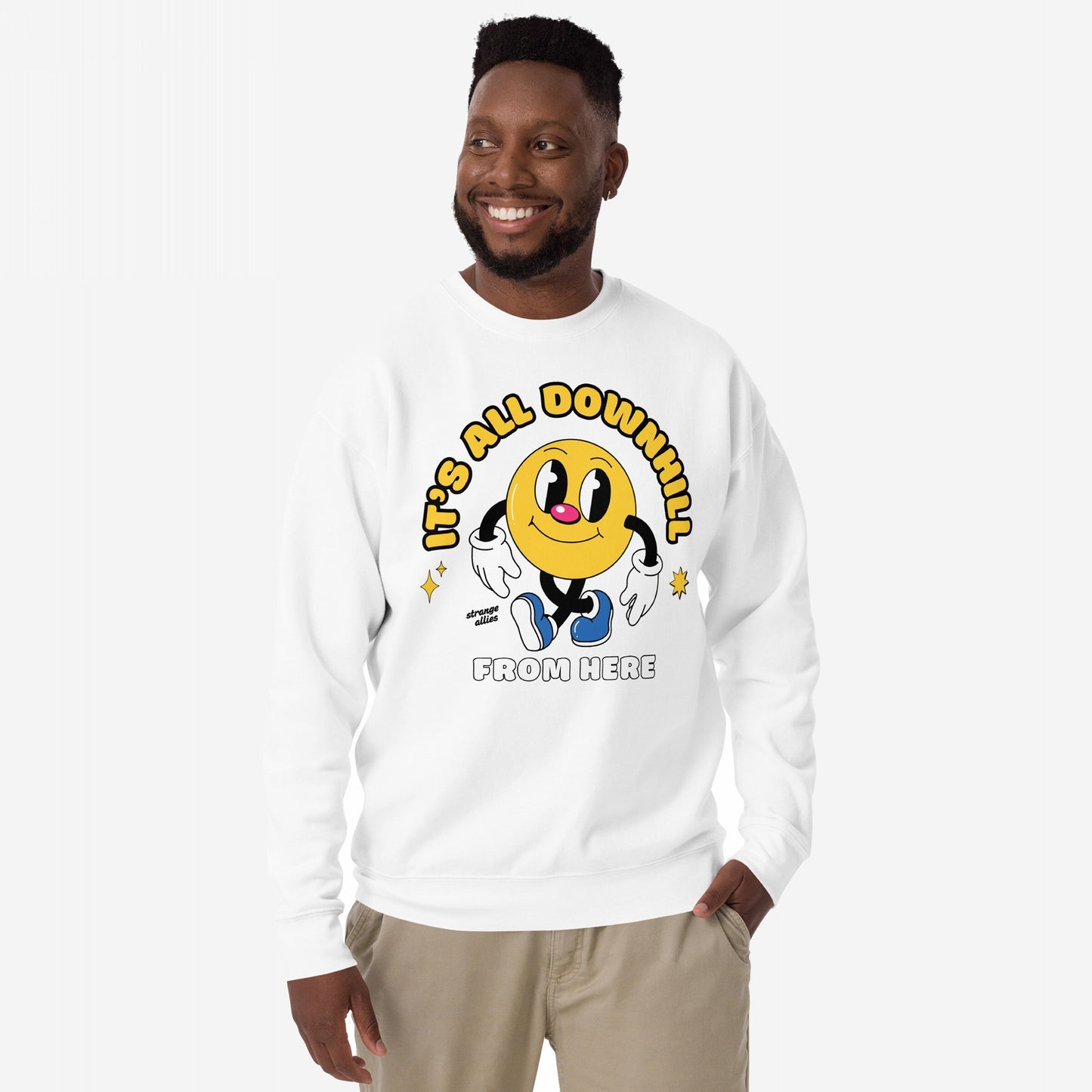 Downhill Hoodie & Sweatshirt features a retro smiley character with IT'S ALL DOWNHILL slogan, embodying a playful cynicism. Modeled by a smiling man, highlighting its casual, relaxed fit.
