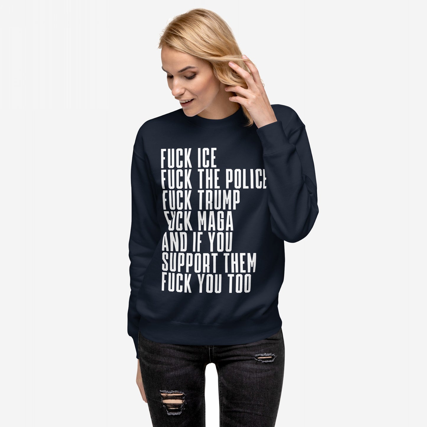 Woman in ripped jeans wearing the Fuck 'Em All Sweatshirt, featuring a bold anti-establishment slogan. She brushes her hair aside, embodying a defiant stance against injustice.