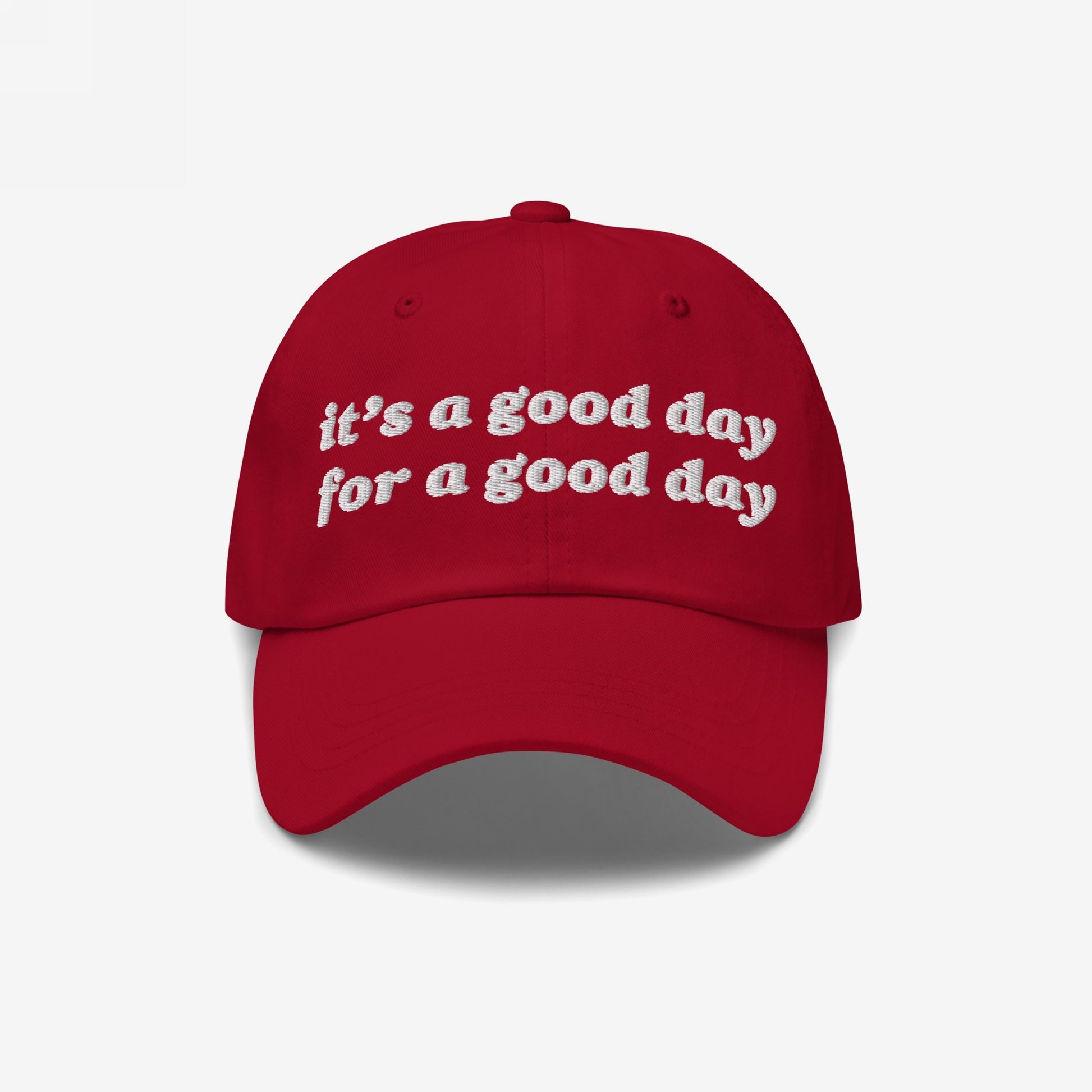 Red Good Day Hat with white embroidered text: it’s a good day for a good day. Perfect for spreading positivity and supporting mental health awareness. Available in various styles.