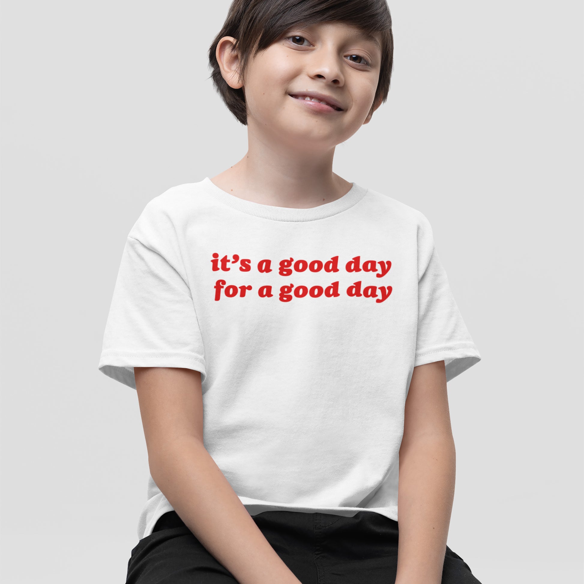 Child in a white Good Day Shirt with bold red text, “it’s a good day for a good day,” embodying positivity and vintage charm, perfect for uplifting moods and spreading smiles.