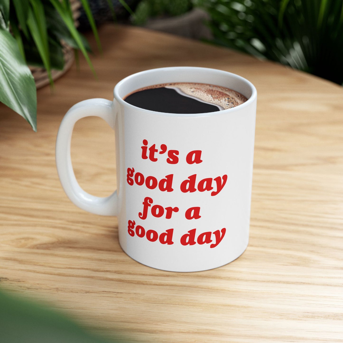 Good Day Mug on a wooden tabletop, filled with coffee, featuring the phrase “it’s a good day for a good day” in bold red letters, embodying positivity and resilience.