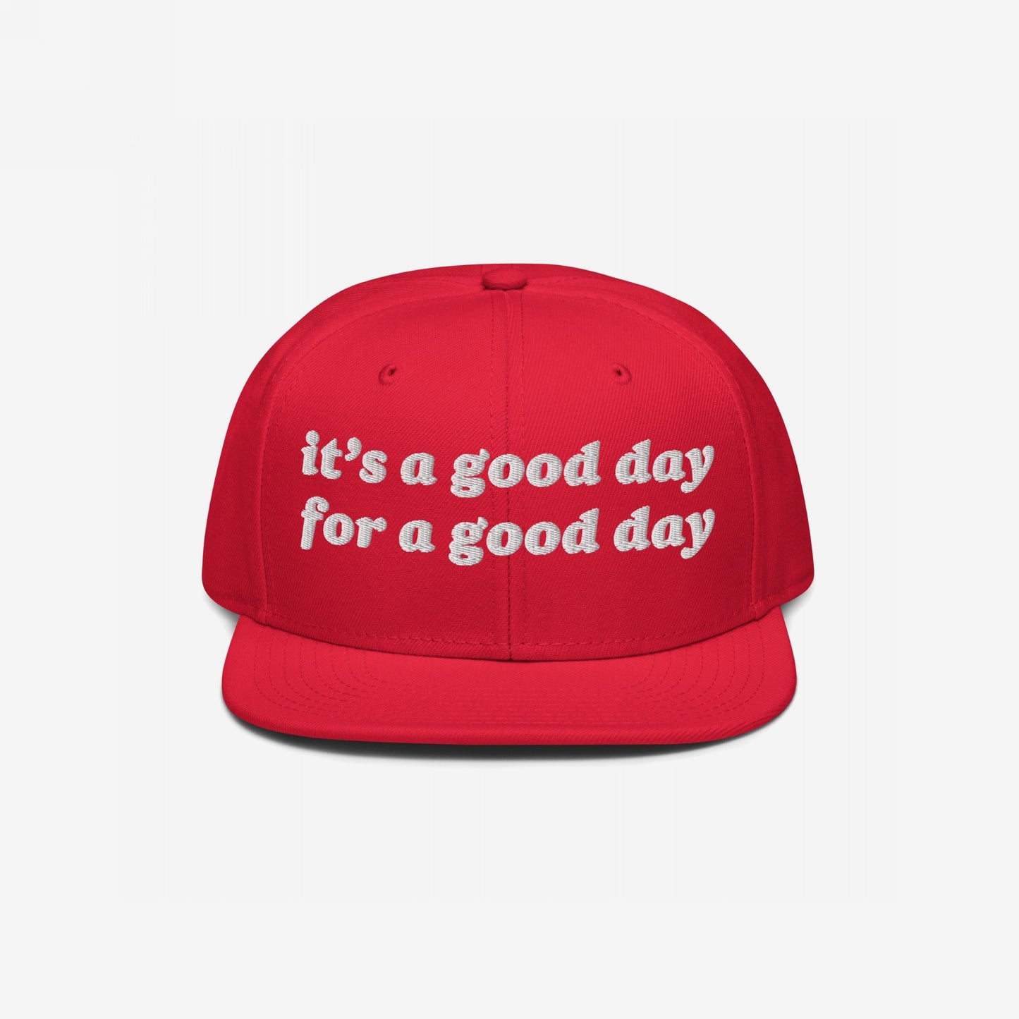 The Good Day Hat features bright red, flat-brim snapback style with white embroidered text, promoting optimism and mental health advocacy through its “it’s a good day for a good day” message.