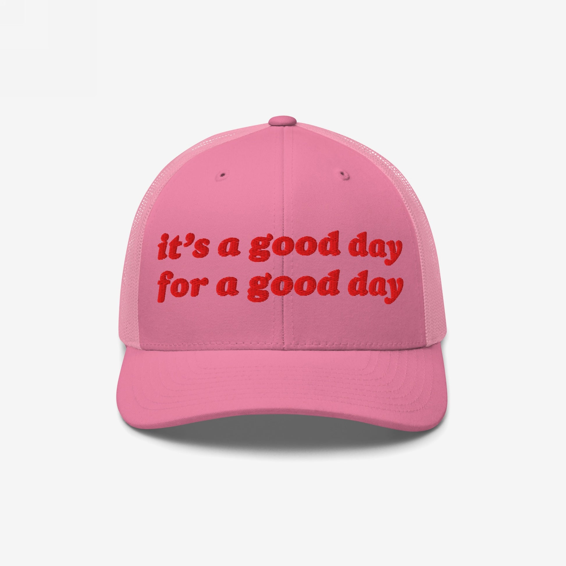Good Day Hat: A pink trucker-style cap with mesh back, featuring bold red embroidery stating “It’s a good day for a good day,” embodying positivity and mental health advocacy.
