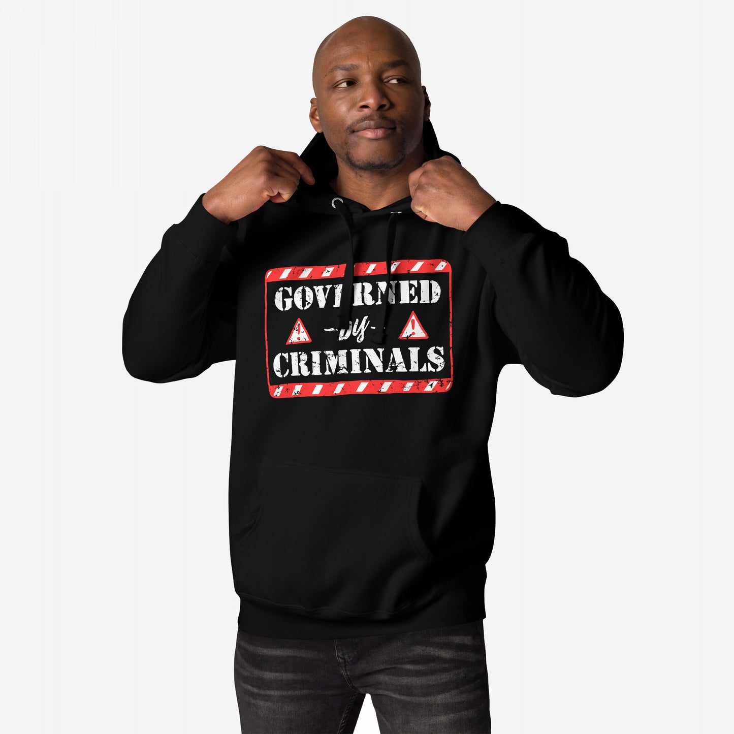 Man wearing the Governed By Criminals Hoodie, featuring a red-and-white stencil warning sign, pulls on the hood's drawstrings, embodying resistance against corruption and power abuse.