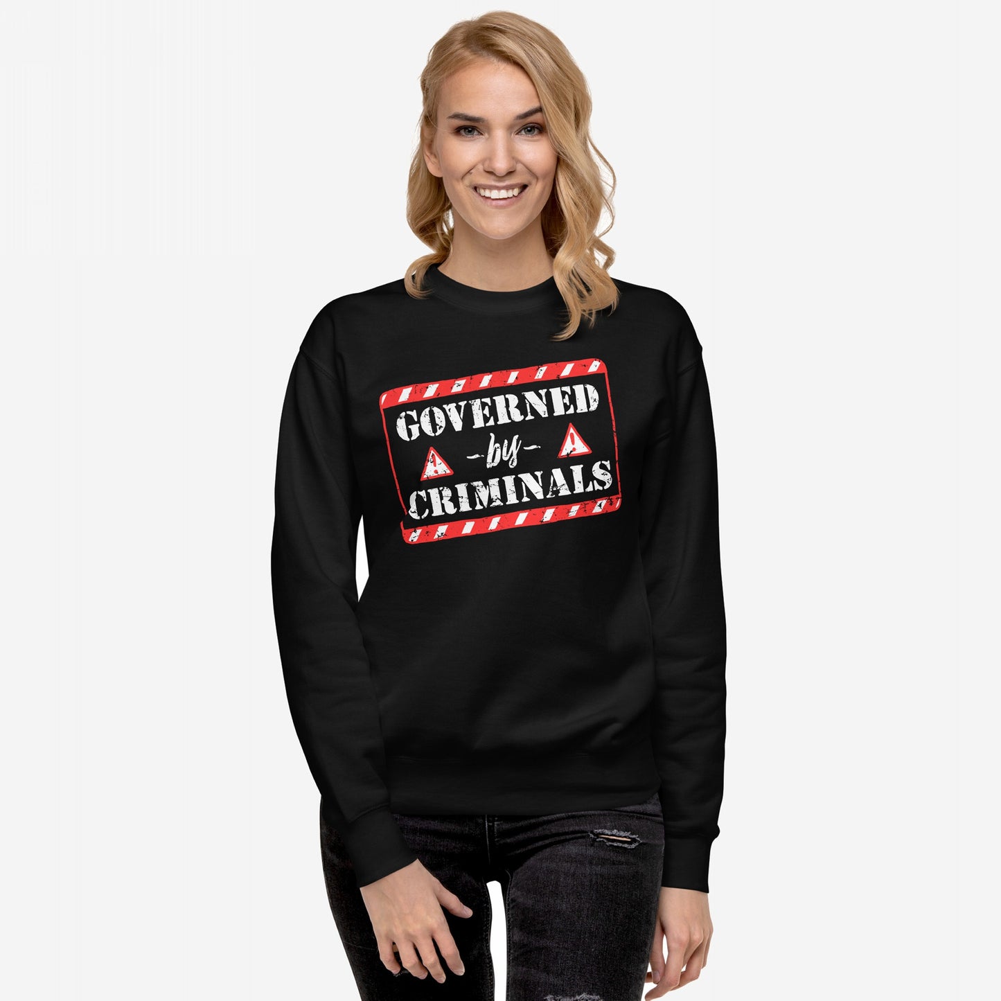 Young woman wearing the Governed By Criminals Hoodie & Sweatshirt, showcasing a bold, red-and-white graphic statement against power hypocrisy. She smiles confidently, embodying resistance through striking apparel.