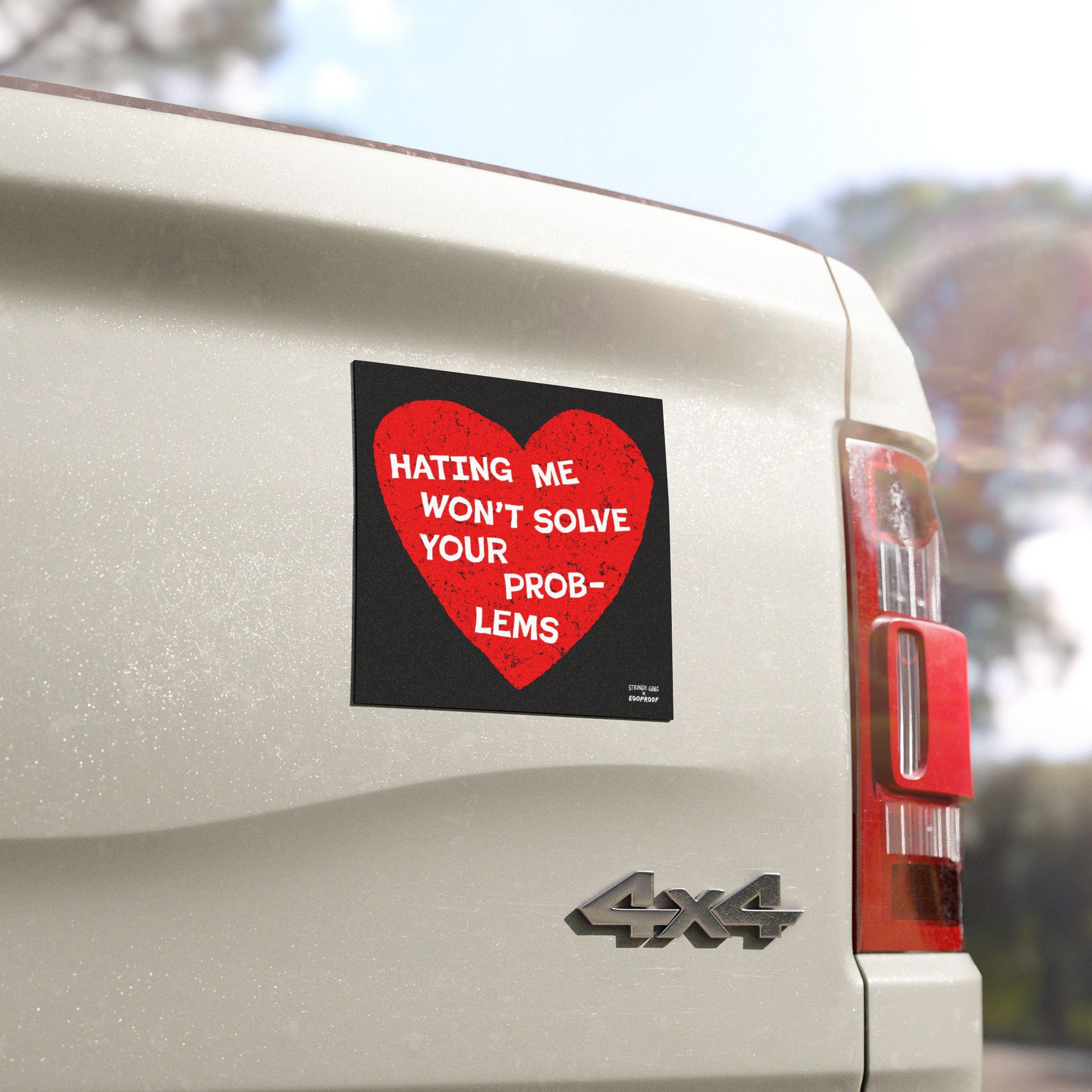 Close-up of the No Hate Sticker & Magnet on a white 4x4 vehicle's tailgate, featuring a distressed red heart and the message “HATING ME WON’T SOLVE YOUR PROBLEMS” in bold white letters.