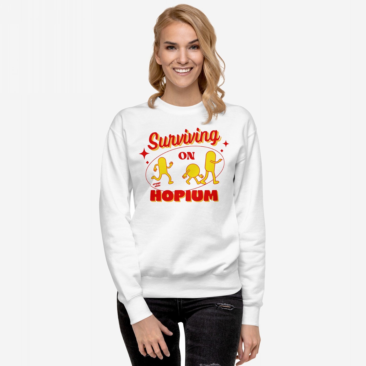 Young woman wearing the Hopium Hoodie & Sweatshirt, featuring Surviving on Hopium graphic with cartoon figures, embodying hopeful optimism. Paired with ripped jeans, perfect for dreamers and reality avoiders.