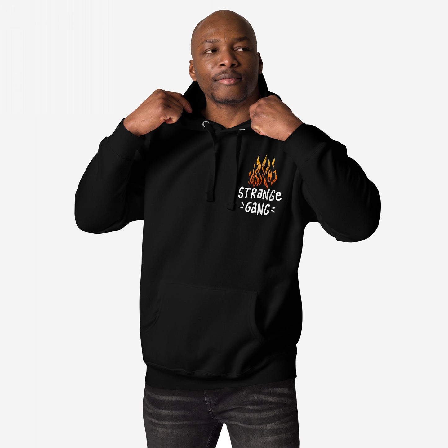 Man wearing ICE Is State Sponsored Terrorism Hoodie, showcasing front flame graphic with STRANGE GANG text, and tugging hood drawstrings, embodying defiance and immigrant justice through bold design.