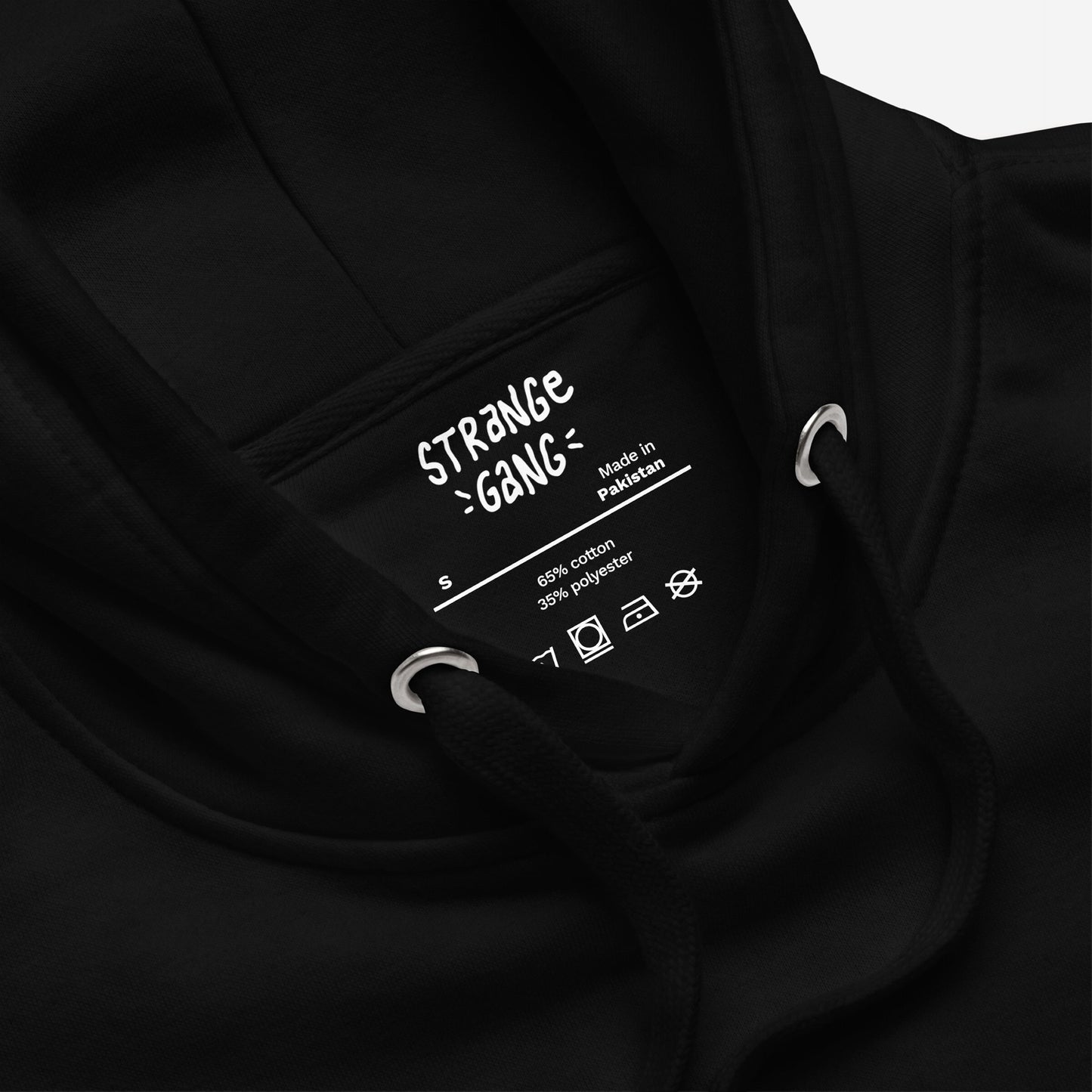 ICE Is State Sponsored Terrorism Hoodie: Close-up of neck area showing label details, including Made in Pakistan, size S, fabric content, and garment-care symbols, with black drawcords and metal eyelets visible.