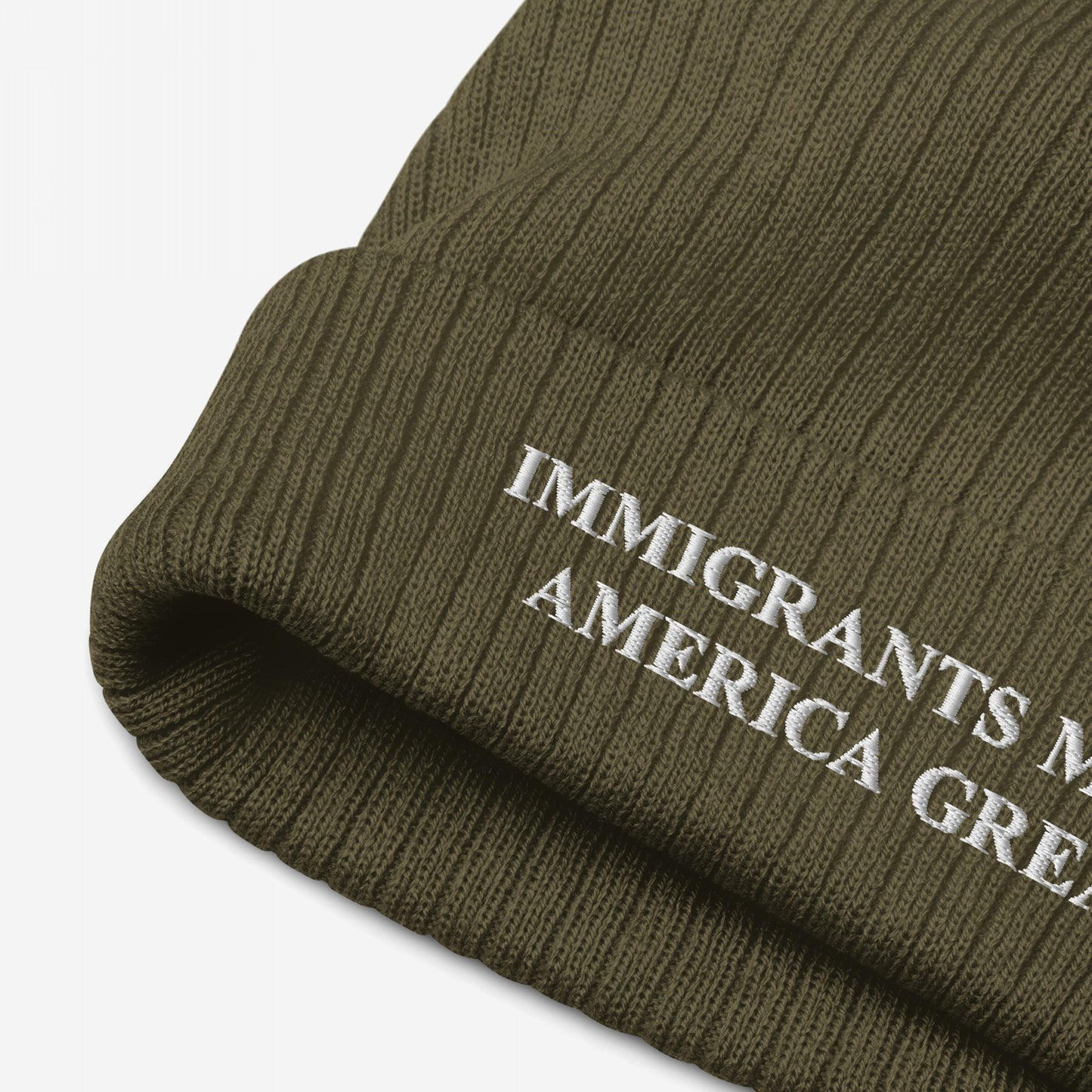 Olive-green rib-knit beanie with the slogan IMMIGRANTS MAKE AMERICA GREAT embroidered in white on the cuff, embodying a bold stance on immigrant rights and equality.