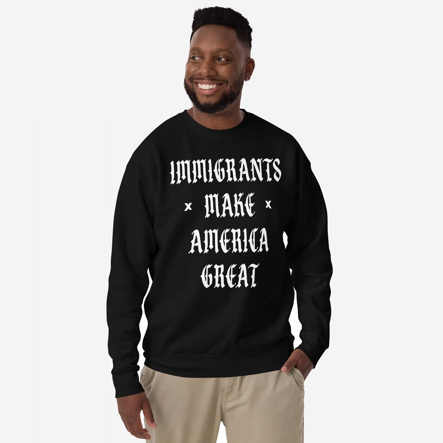 Smiling man models the Immigrants Make America Great Sweatshirt featuring bold white Old English text, advocating for immigrant pride and protest against racism and nationalism.
