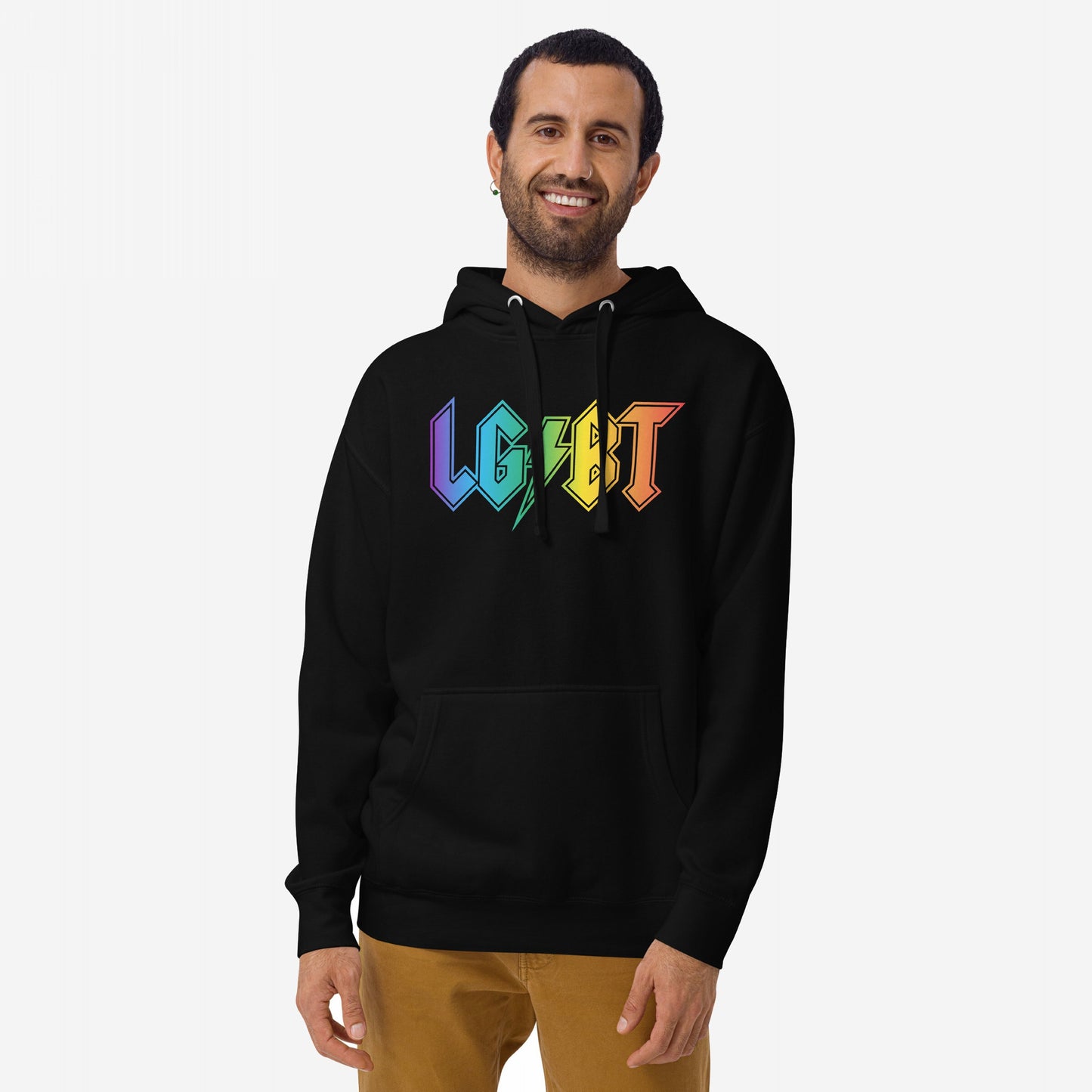 Smiling man wearing the LGBTQ Rocks Hoodie with LGBT in rainbow colors, embodying pride and solidarity, paired with light-brown pants against a plain background.