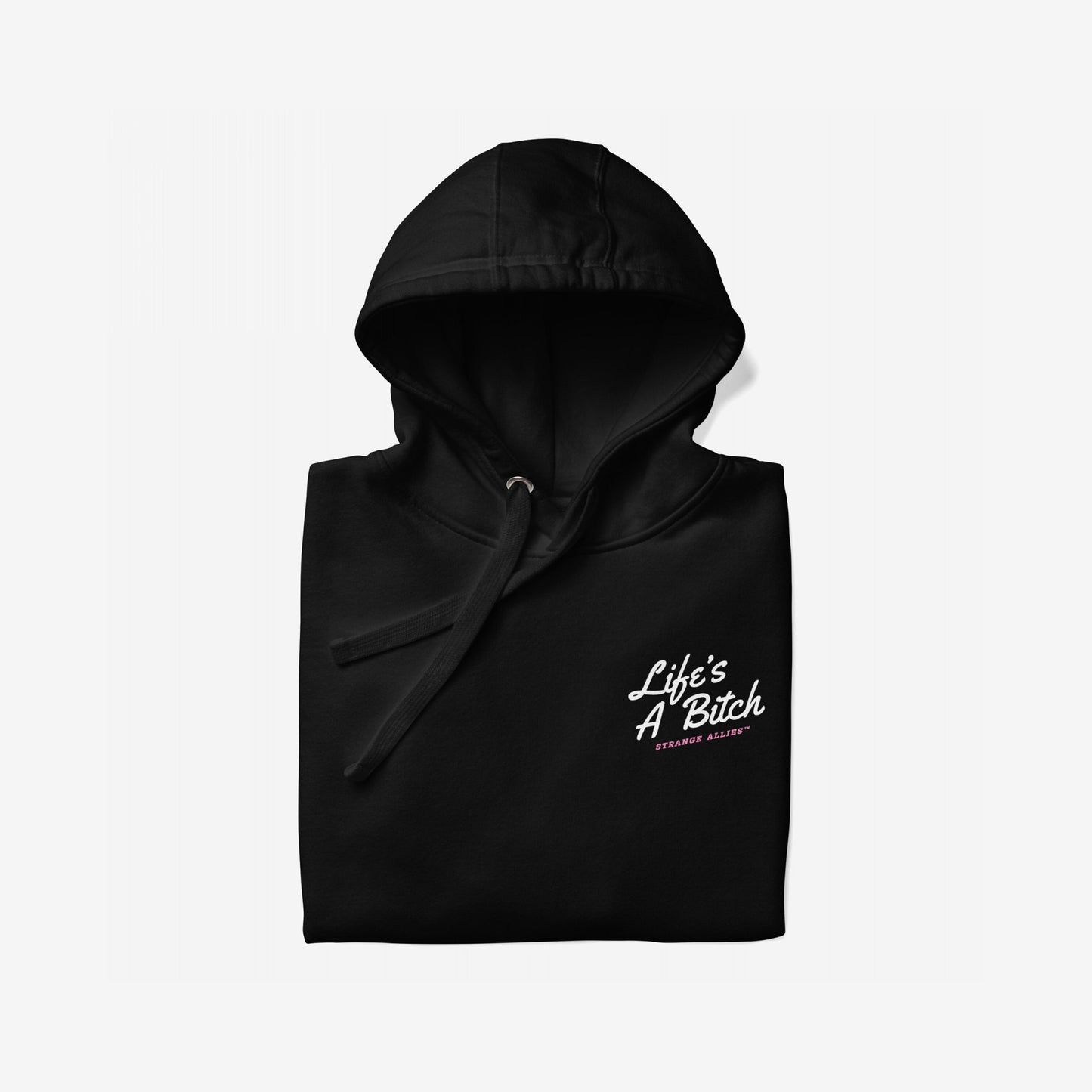Black pullover hoodie titled Life's A Bitch Hoodie & Sweatshirt with a white slogan and pink text, embodying unapologetic realism. Hood and drawstrings visible, laid on a light background.
