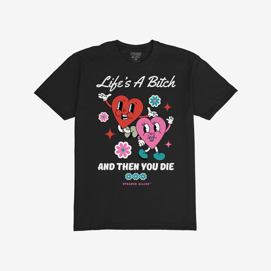 Life's A Bitch T-shirt features vintage-cartoon hearts and flowers, blending cheerful design with blunt humor. Ideal for those who embrace truth with style, available in various fits.