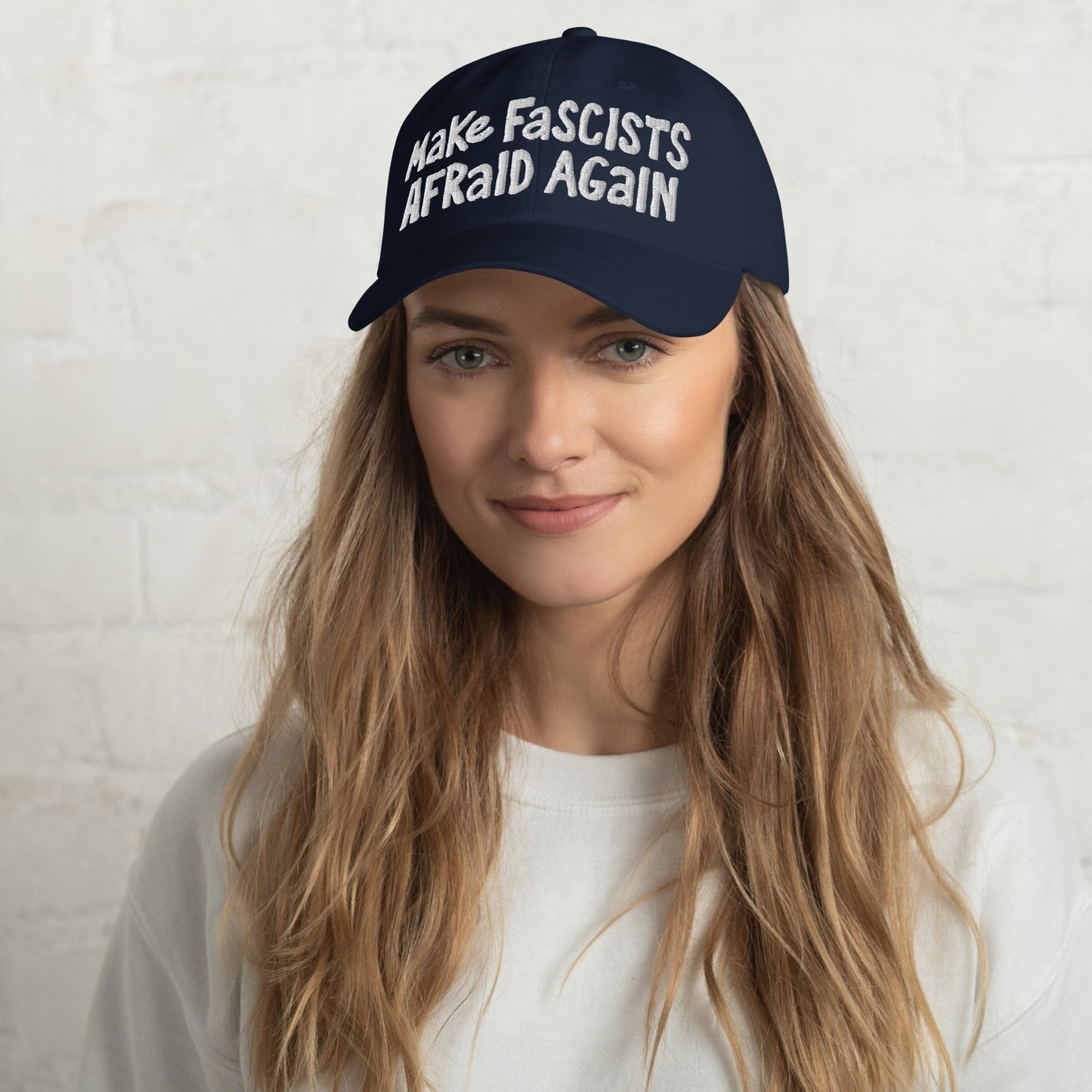 Young woman wearing the Make Fascists Afraid Again hat, featuring bold, hand-drawn embroidery on a navy baseball cap, embodying a message of unapologetic resistance and activism.