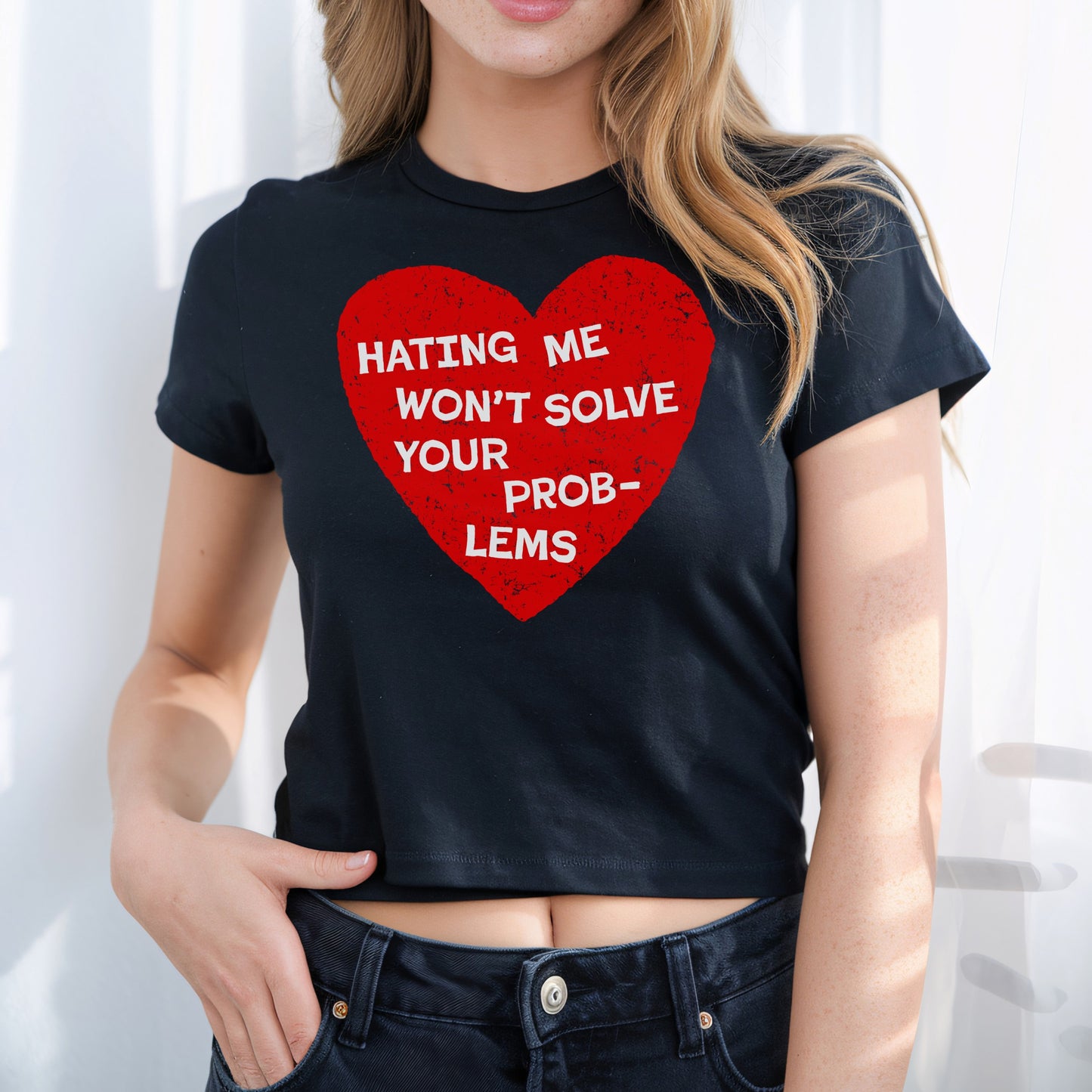 No Hate Women's Baby Tee features a bold red heart with Hating Me Won’t Solve Your Problems text, promoting love and equality. Worn with dark jeans, showcasing midriff.