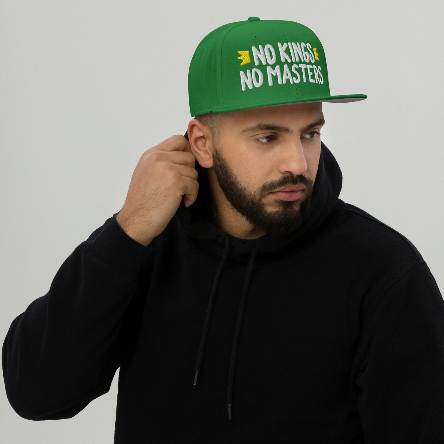 Young man wearing a No Kings No Masters hat with bold white embroidery, showcasing a rebellious spirit and anti-authoritarian stance, perfectly aligning with the store's ethos of supporting equality and justice.