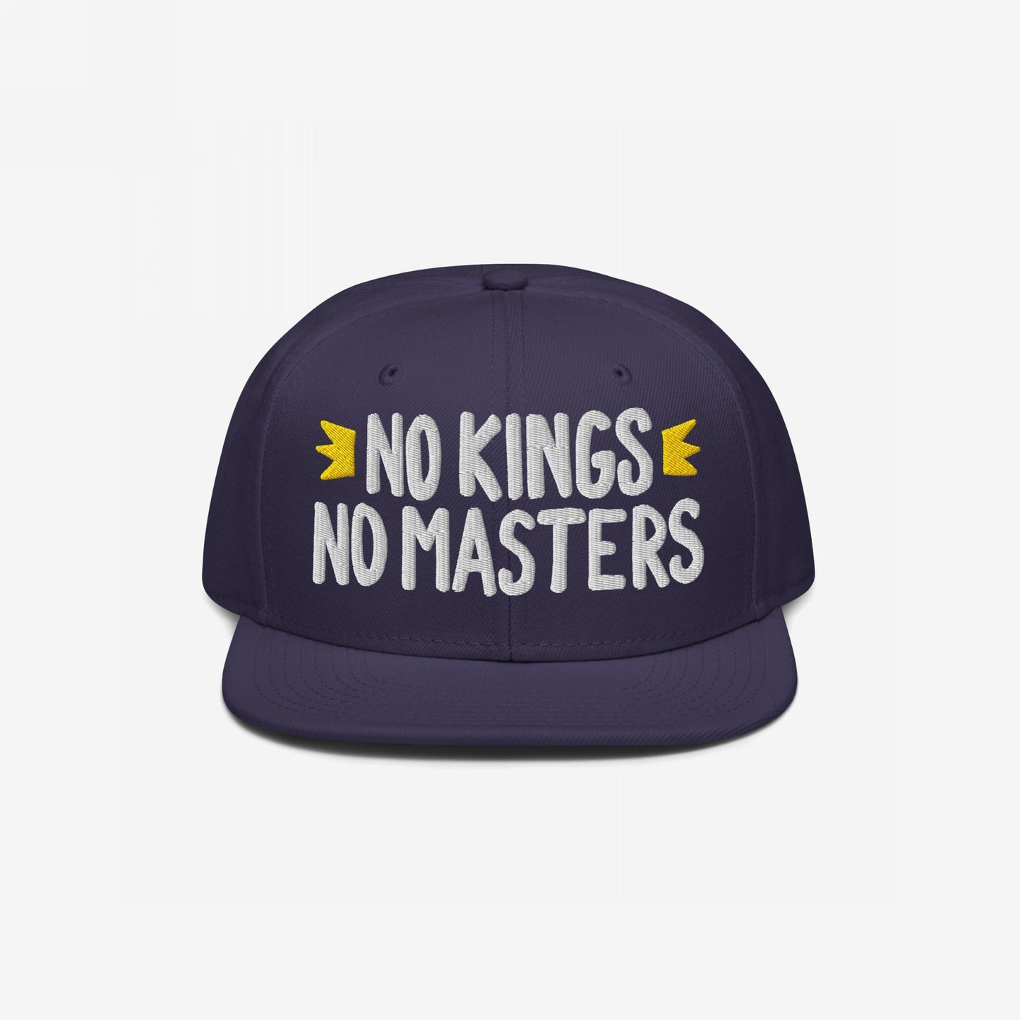 No Kings No Masters Hat featuring white embroidered slogan with yellow crown accents on a navy-blue flat-bill snapback, embodying rebellious style and defiance.