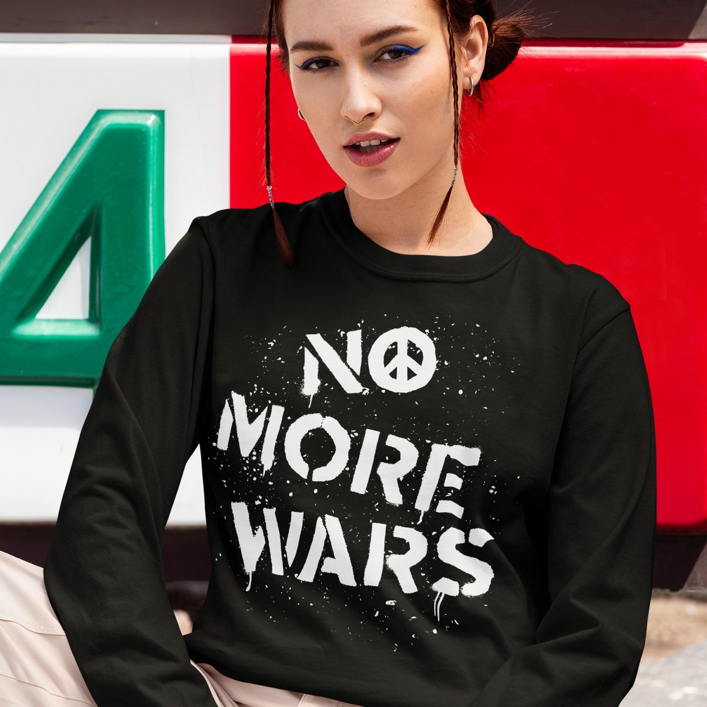 A young woman models the No More Wars T-shirt, featuring a bold, white paint-splattered slogan and peace symbol, embodying a strong anti-violence message.